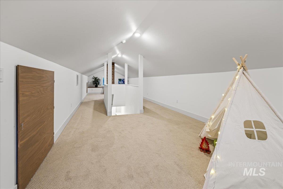 Bonus room featuring vaulted ceiling and light colored carpet