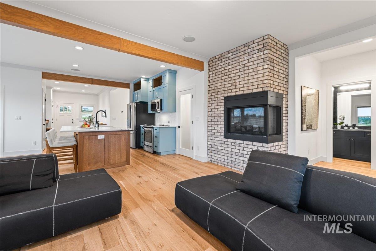 Living room with beamed ceiling, light wood-style floors, recessed lighting, and a fireplace
