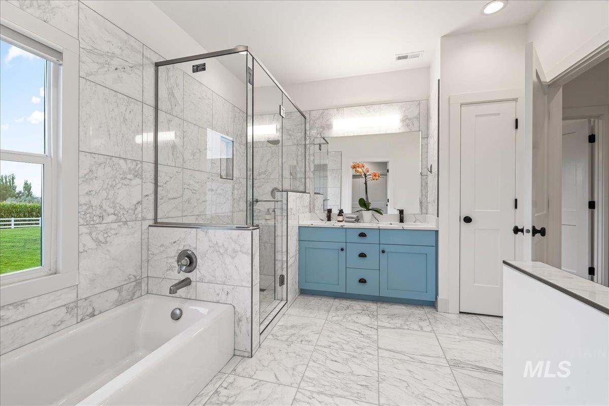 Bathroom with a bath, double vanity, a stall shower, and light marble finish flooring