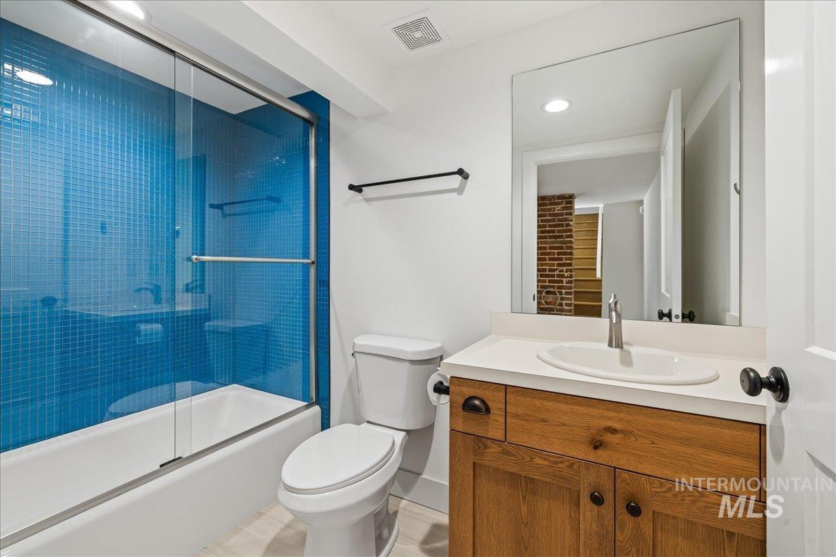 Bathroom with vanity, combined bath / shower with glass door, and recessed lighting