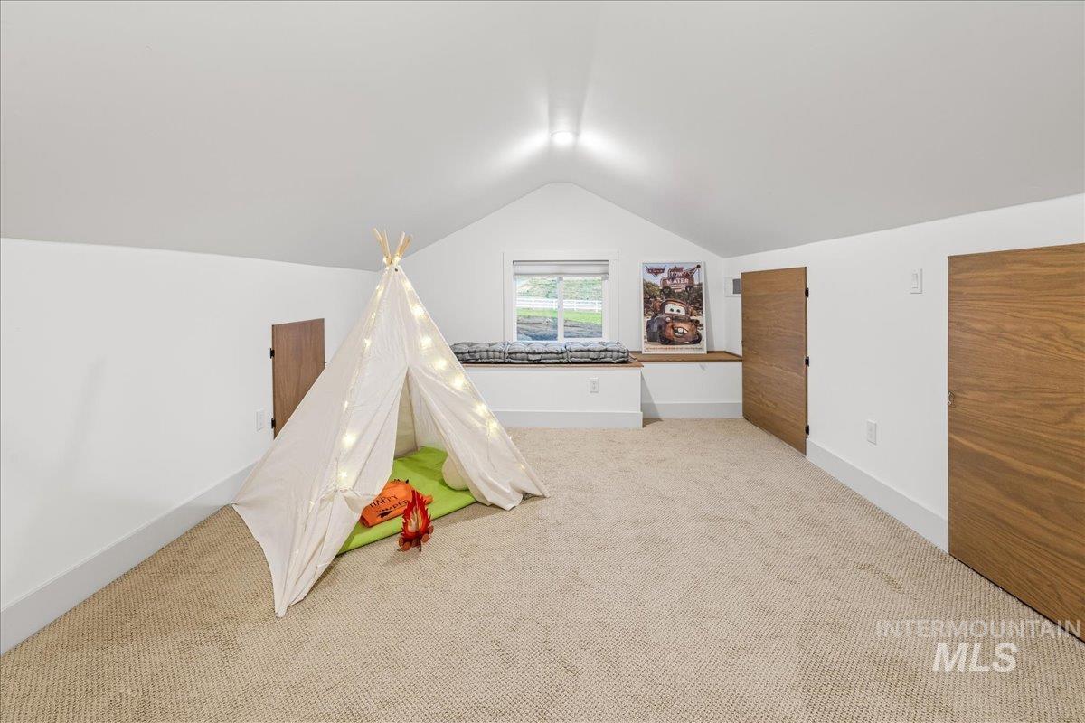 Recreation room with carpet floors and vaulted ceiling