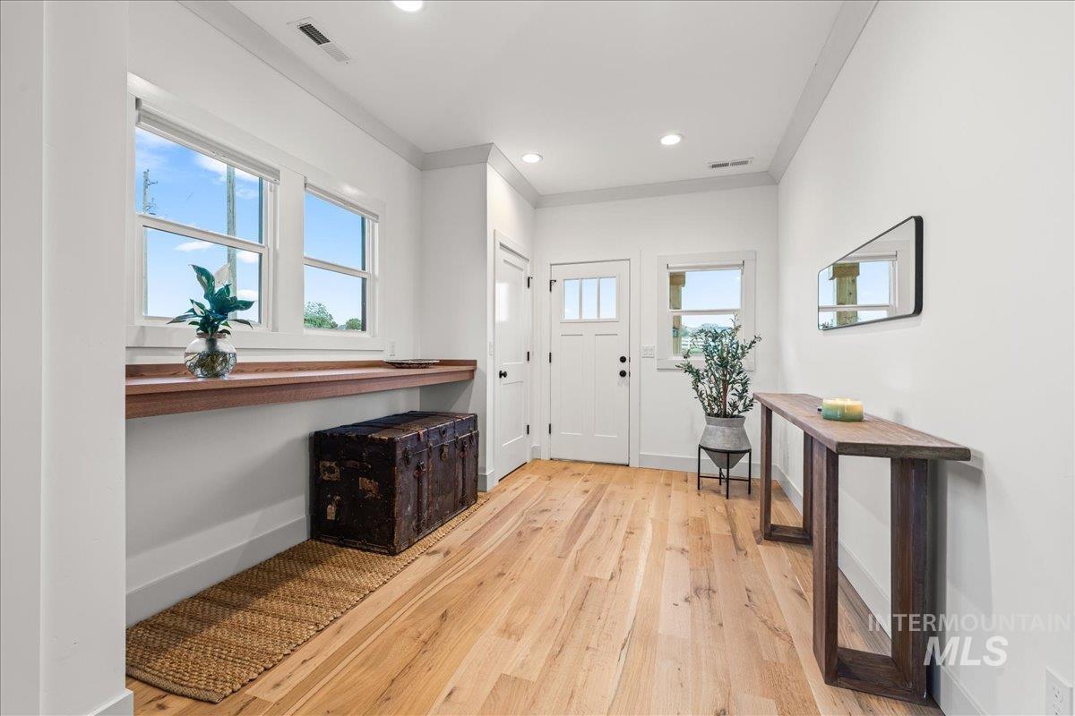 Foyer with light wood-type flooring, crown molding, and recessed lighting