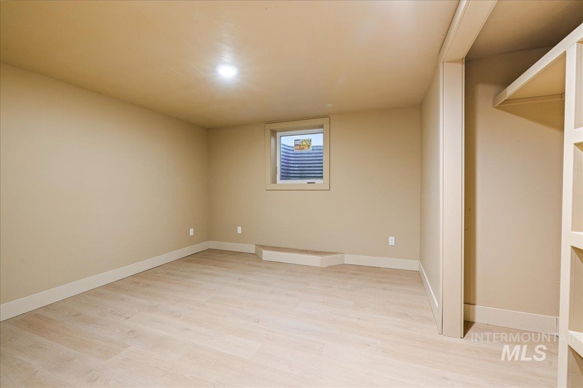Finished below grade area with light wood-style flooring and baseboards