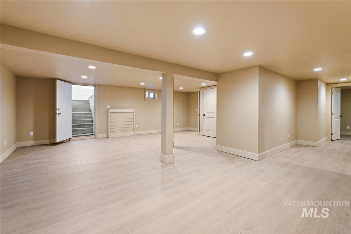 Finished below grade area featuring recessed lighting, light wood finished floors, and stairway