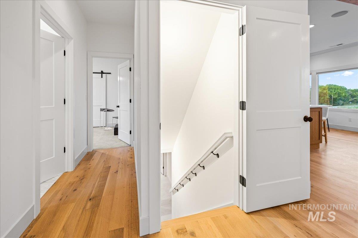 Hall with an upstairs landing and light wood-style flooring