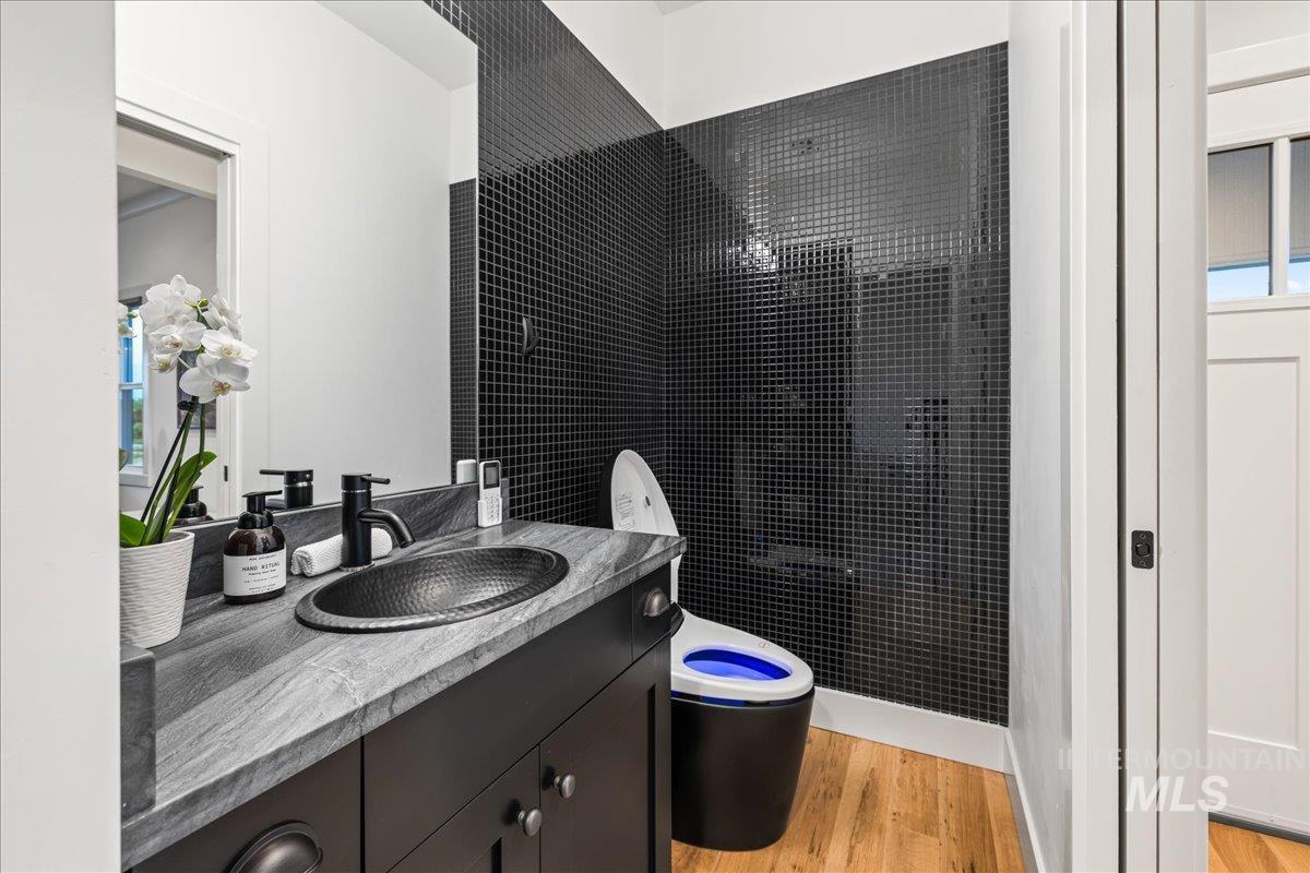 Full bathroom with light wood finished floors, vanity, and a tile shower