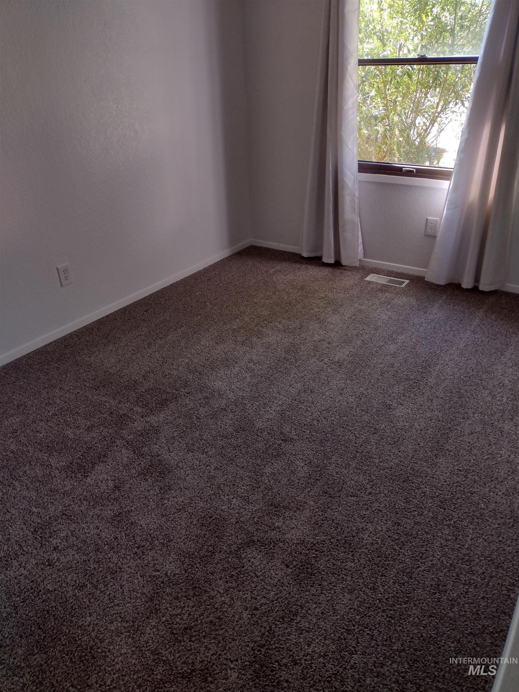 Spare room with dark carpet and baseboards