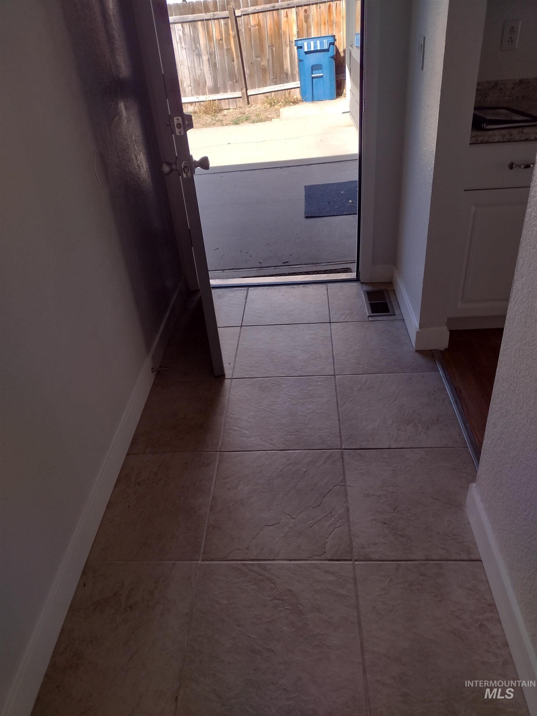 Hallway with light tile patterned floors and a textured wall
