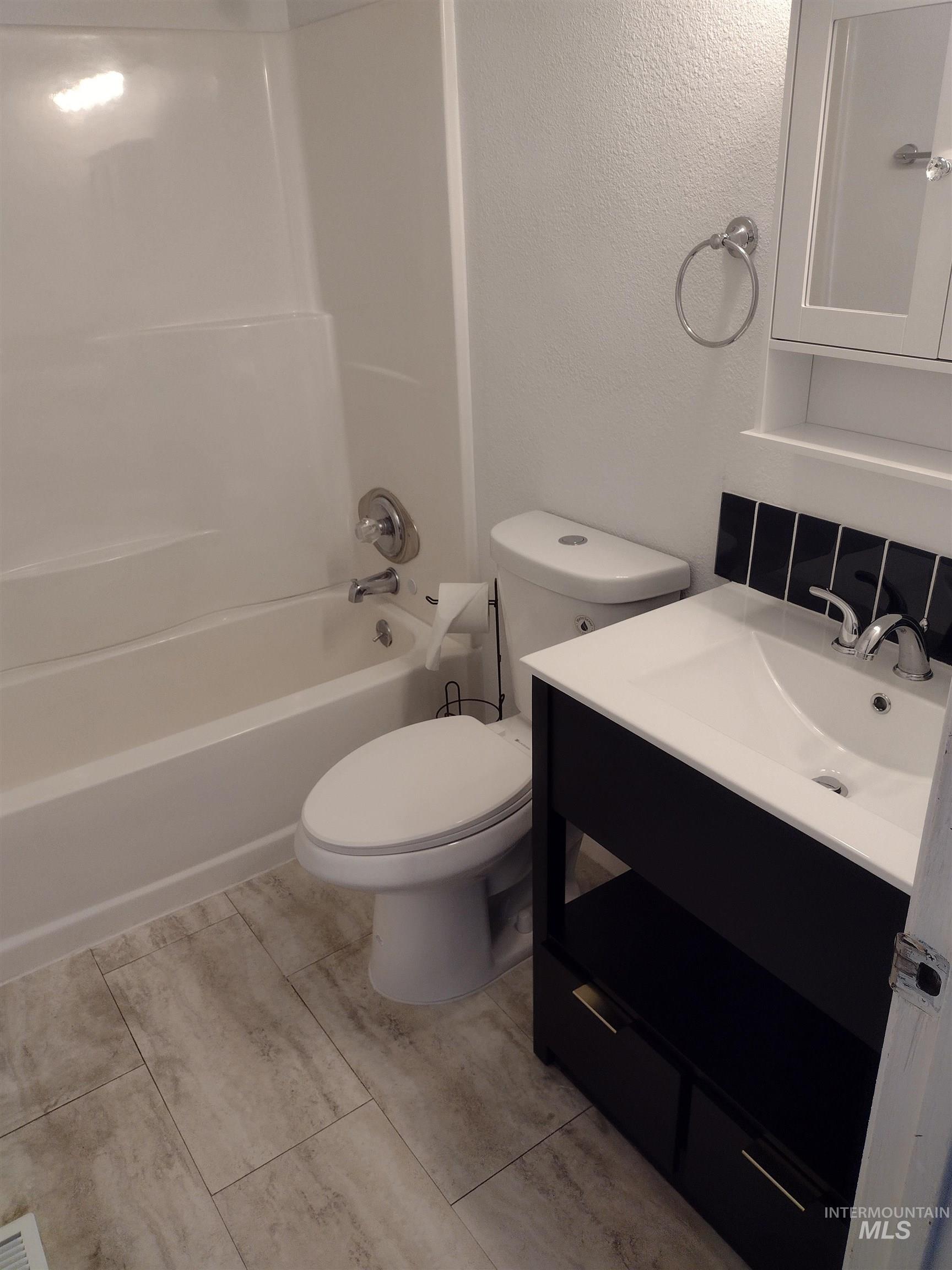 Bathroom featuring shower / washtub combination, vanity, a textured wall, and light tile patterned floors