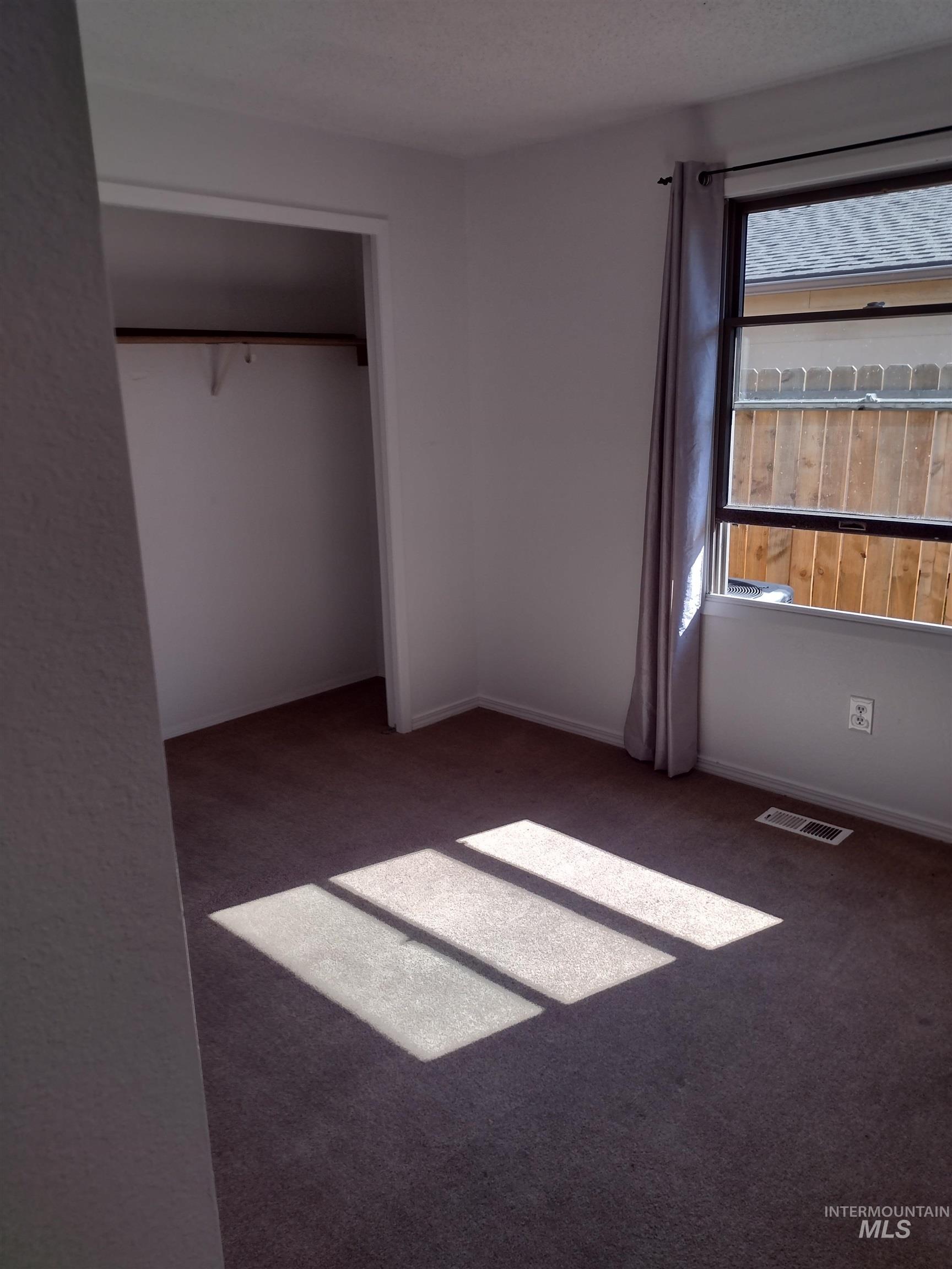 Unfurnished bedroom with dark carpet and a closet