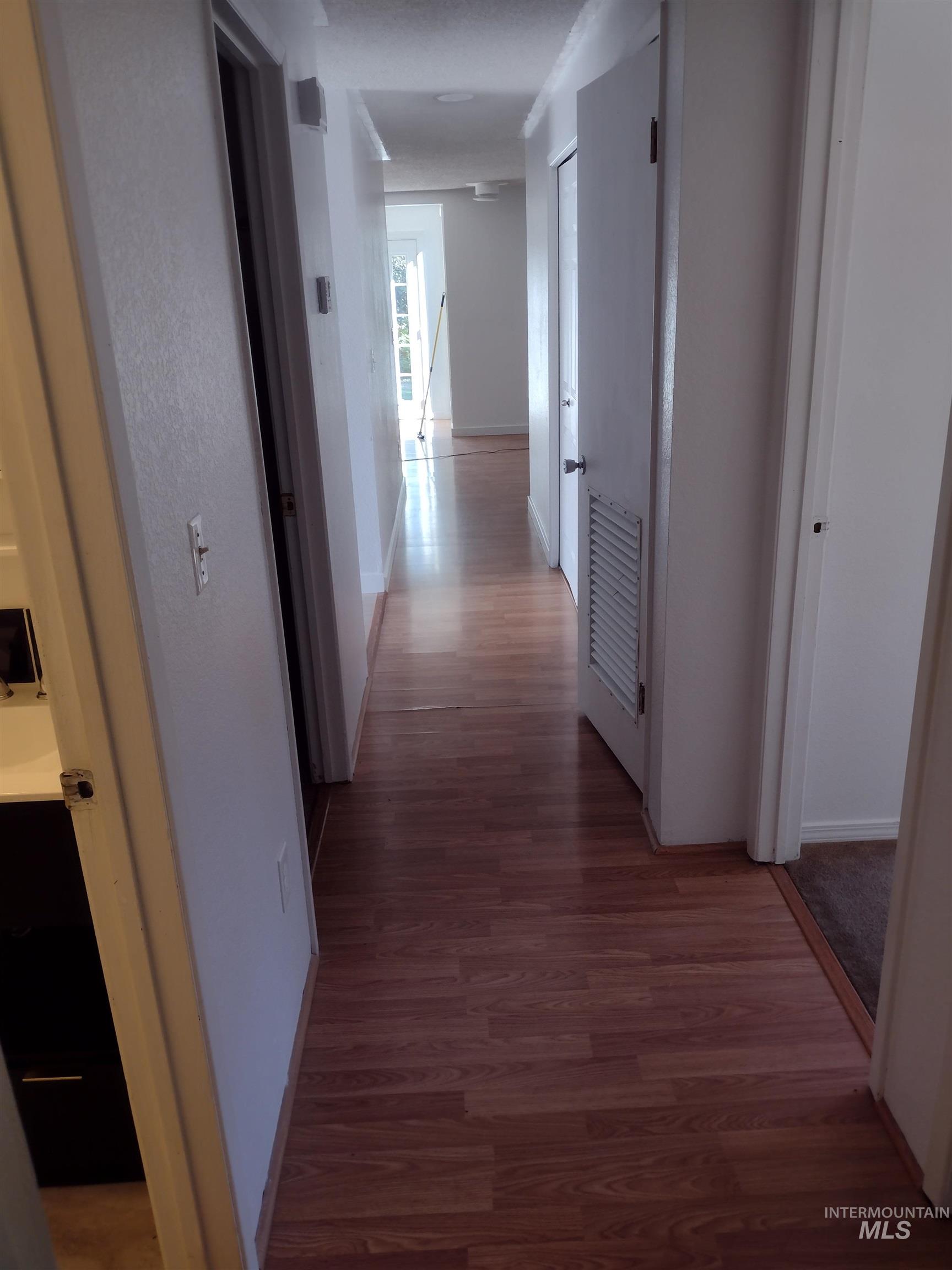 Hallway featuring baseboards and dark wood-style floors