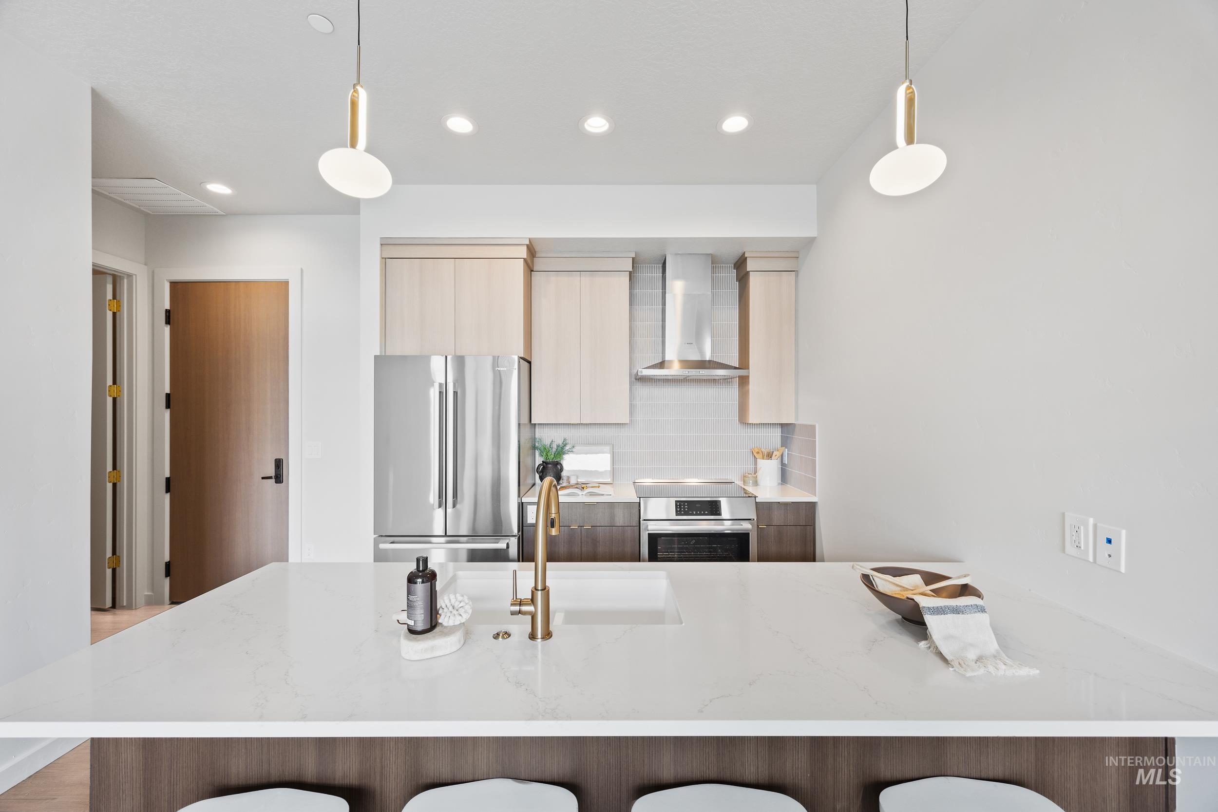 Kitchen with decorative backsplash, light stone countertops, modern cabinets, appliances with stainless steel finishes, and a peninsula