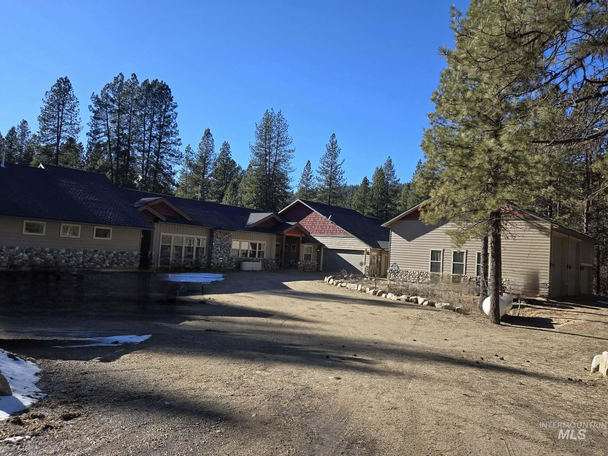 Ranch-style house featuring stone siding and a patio area