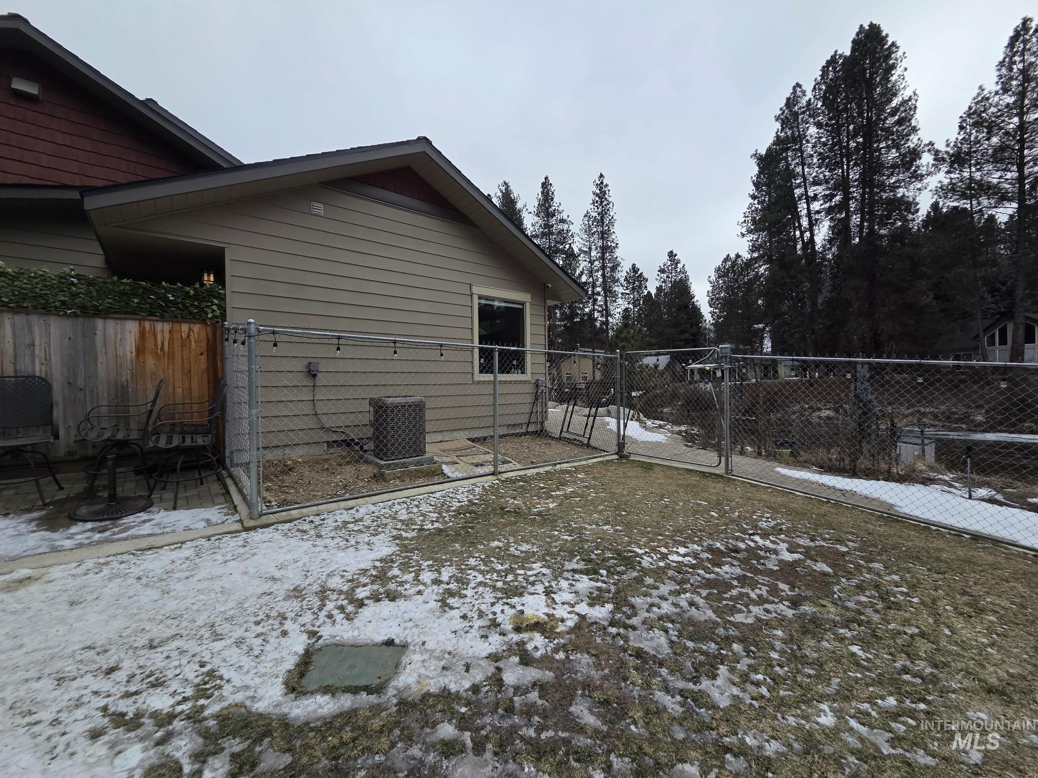 View of snow covered exterior with a gate and a central AC unit