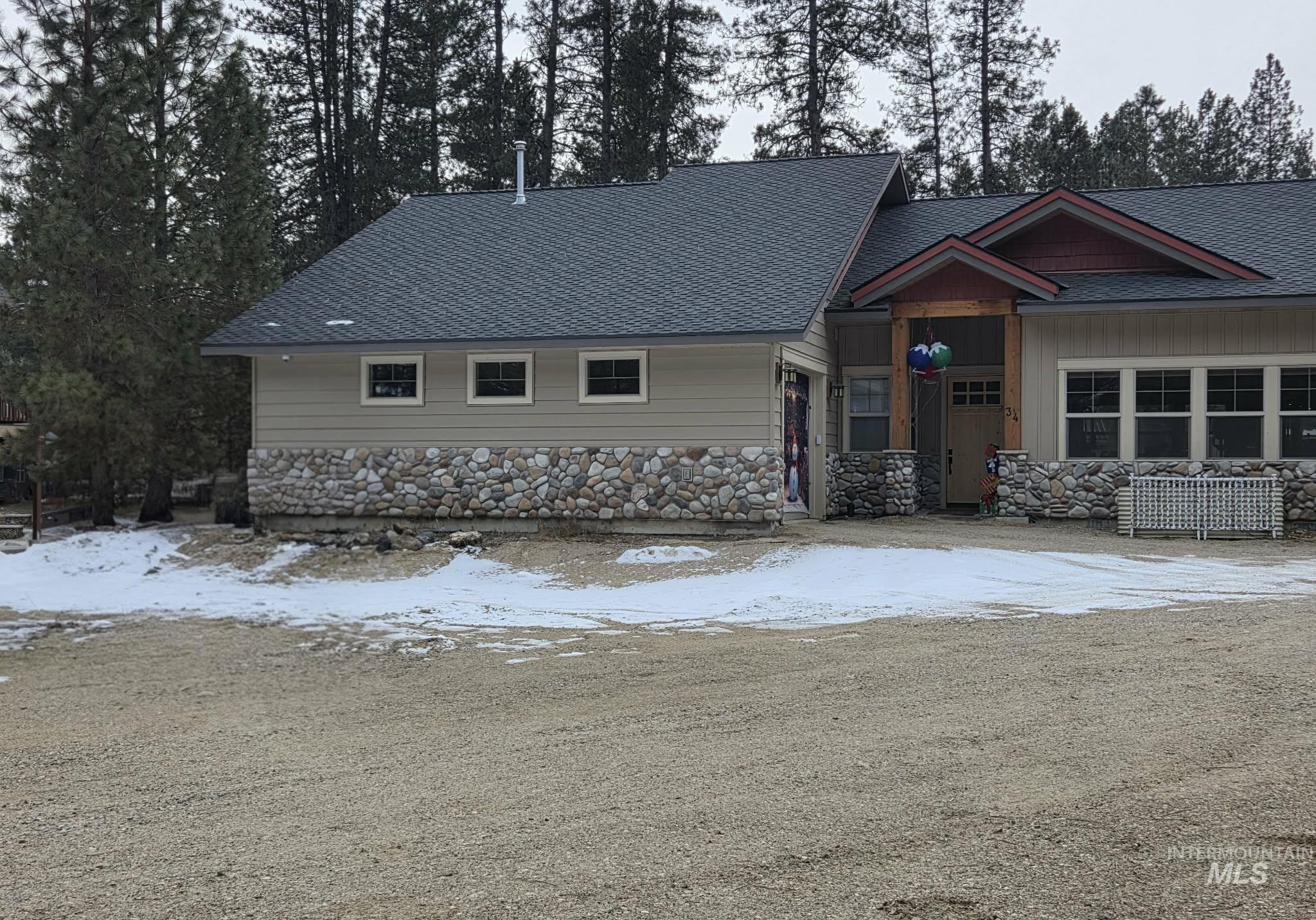 View of front of home featuring a shingled roof and stone siding