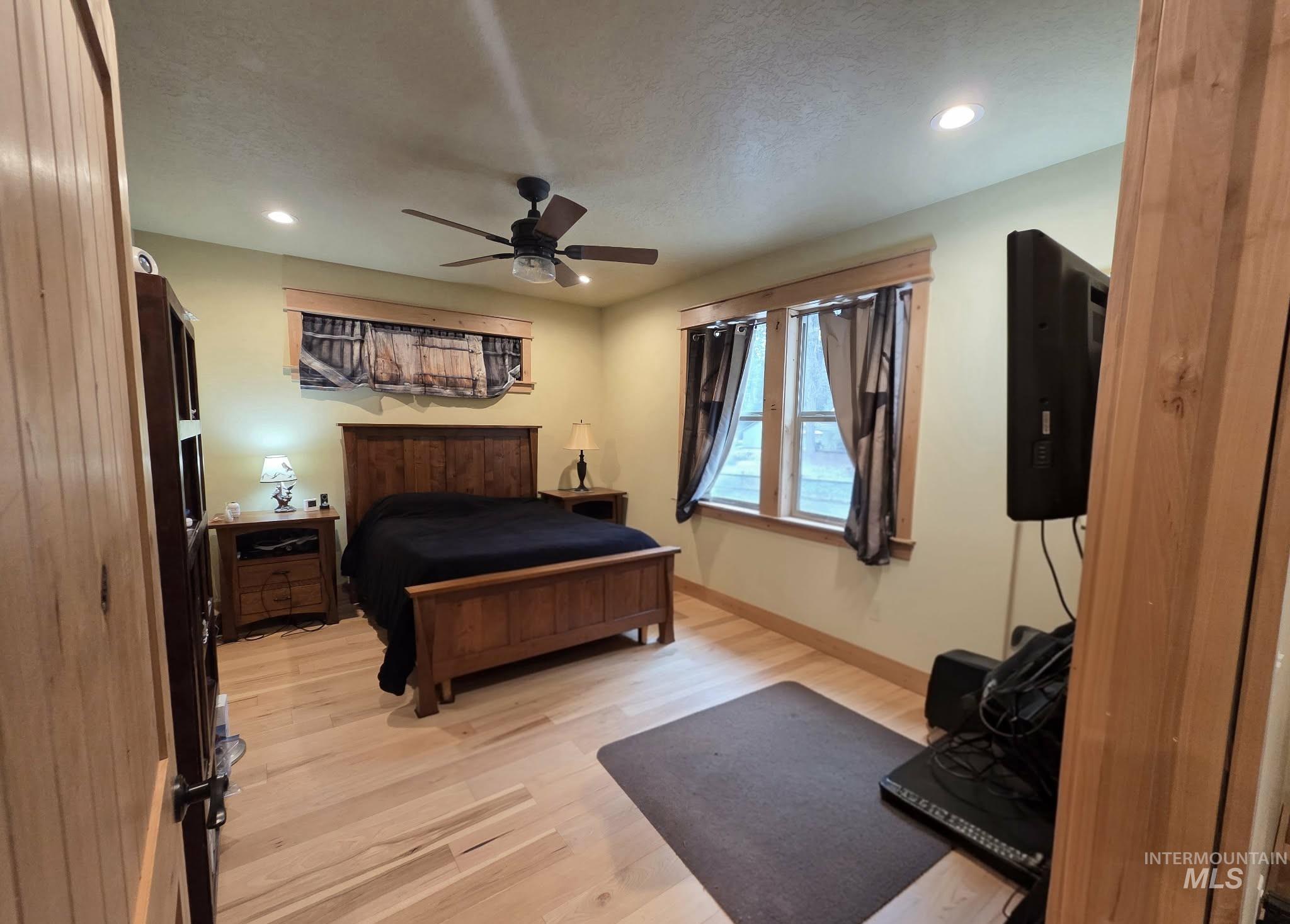 Bedroom with light wood-type flooring, recessed lighting, ceiling fan, and a textured ceiling