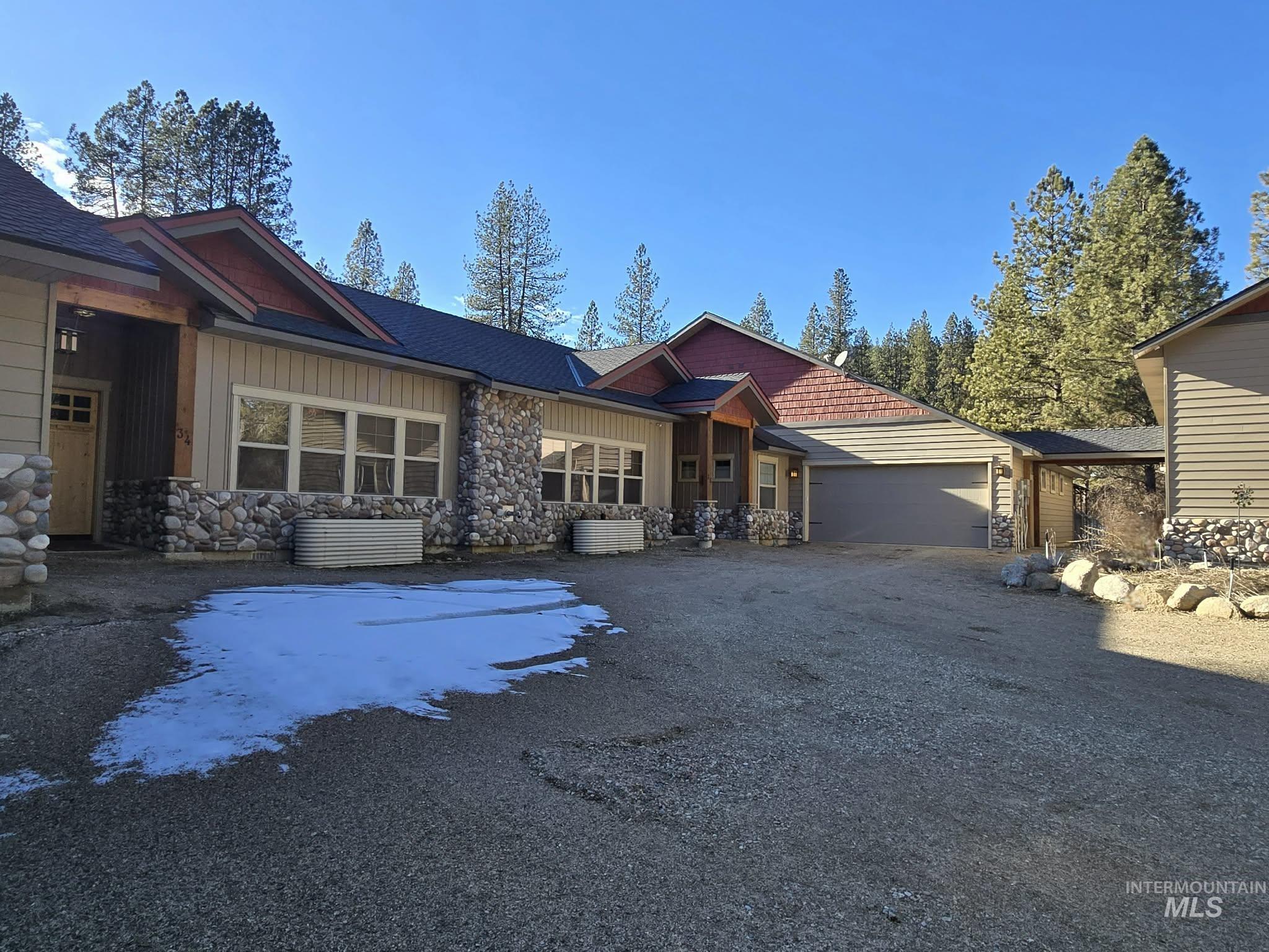 View of front of house with board and batten siding, an attached garage, stone siding, and driveway