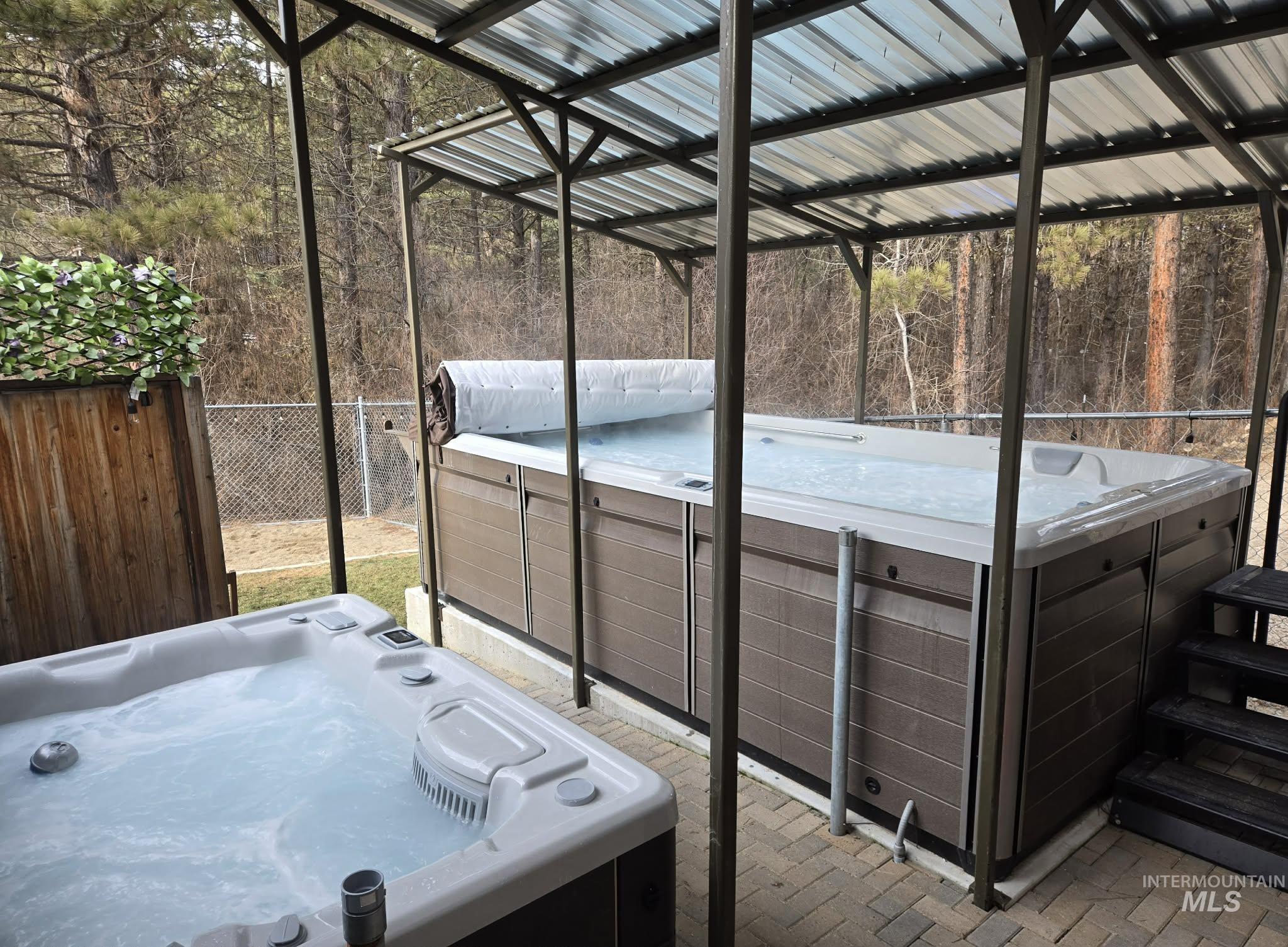 View of patio with a hot tub and a wooded view