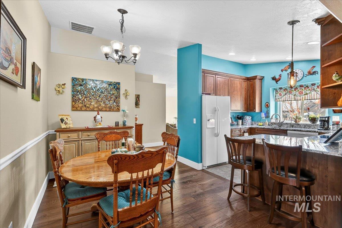 Dining area featuring dark wood-style floors and a chandelier