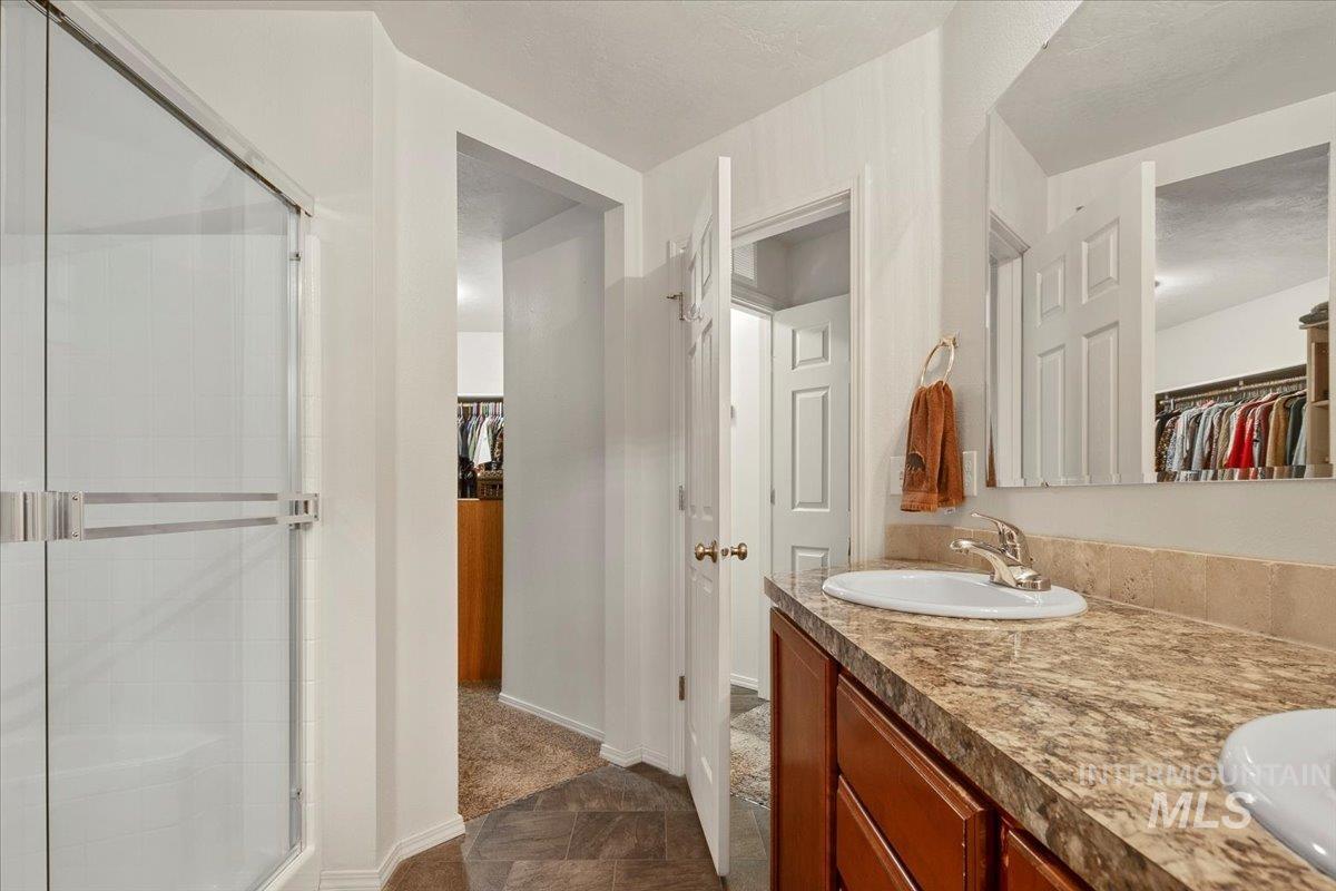 Full bath with a walk in closet, double vanity, and a stall shower
