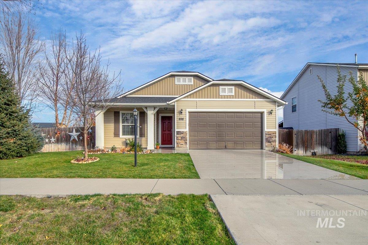 Craftsman inspired home featuring concrete driveway, an attached garage, covered porch, and stone siding