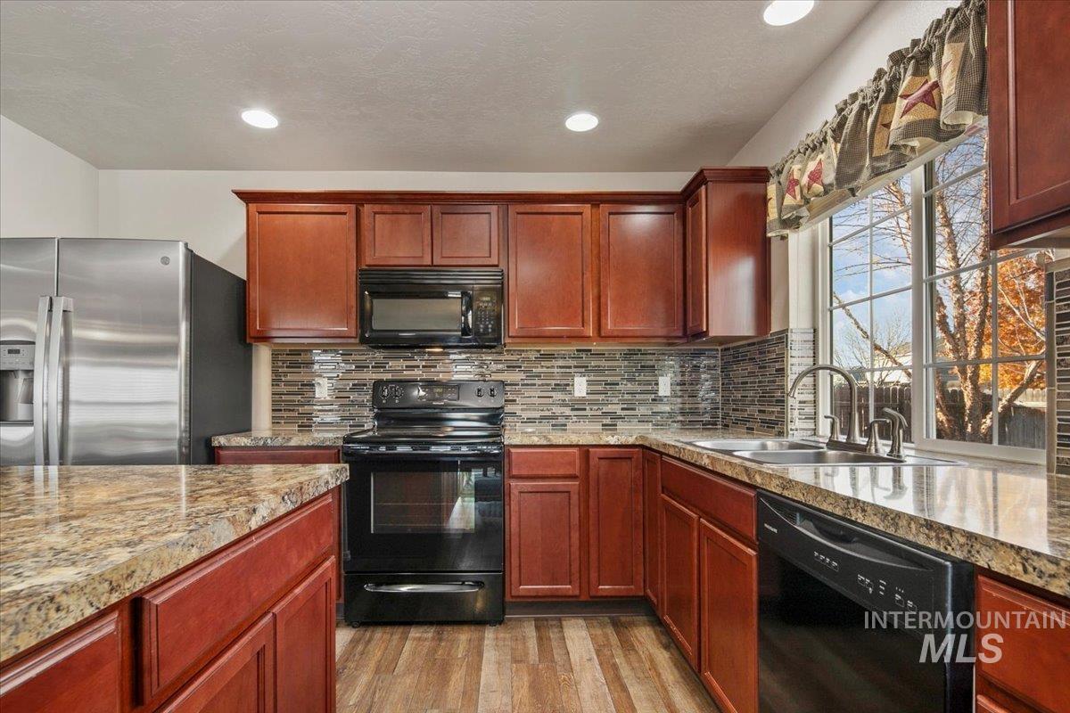 Kitchen featuring black appliances, tasteful backsplash, light wood finished floors, recessed lighting, and reddish brown cabinets