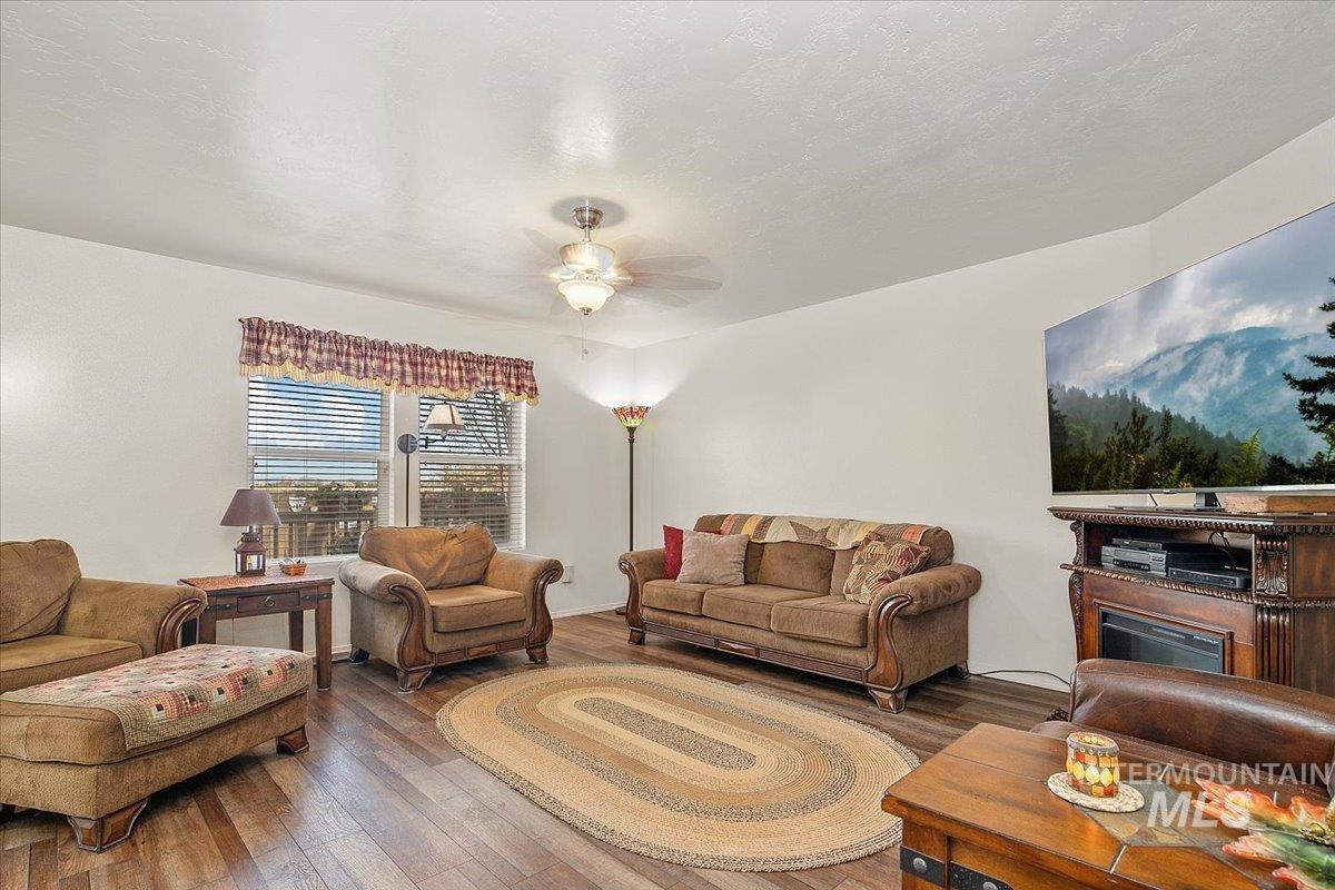 Living room with hardwood / wood-style flooring, ceiling fan, and a textured ceiling