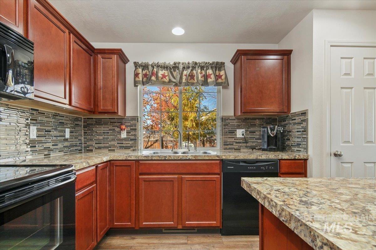 Kitchen featuring black appliances, reddish brown cabinets, light wood-type flooring, backsplash, and recessed lighting