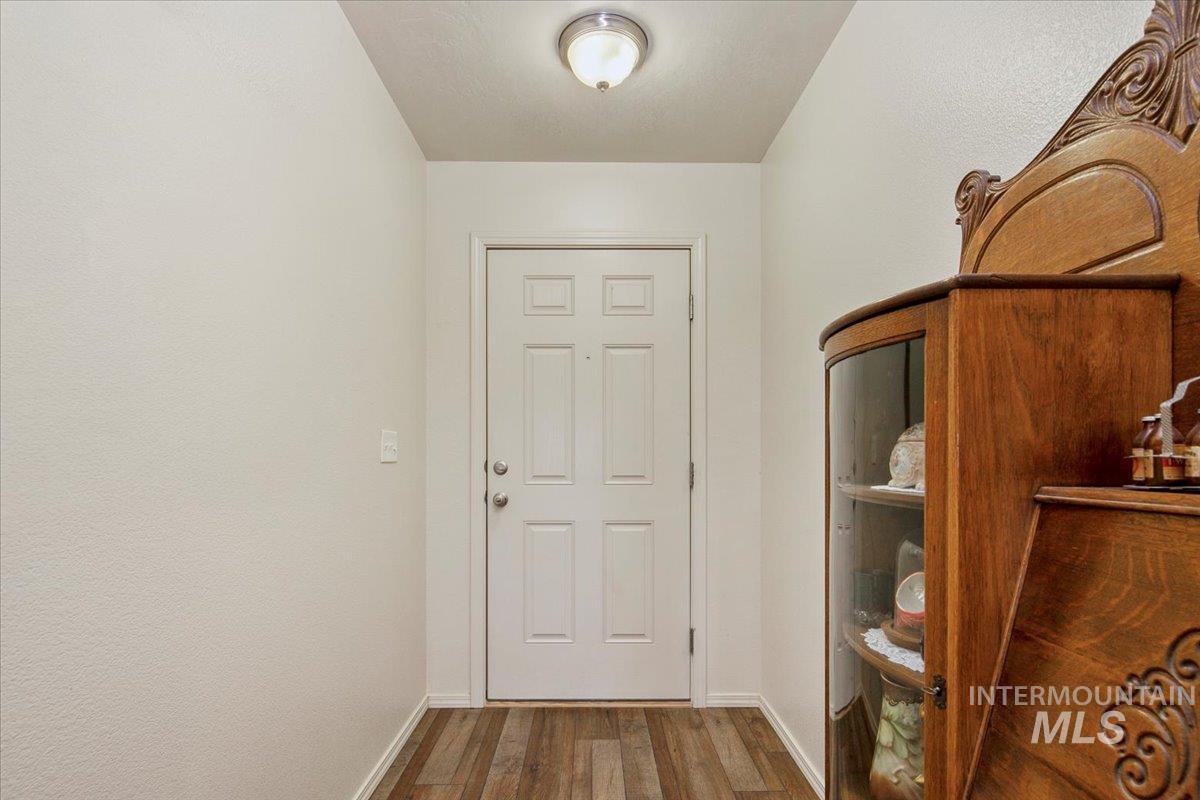 Doorway with wood finished floors and baseboards