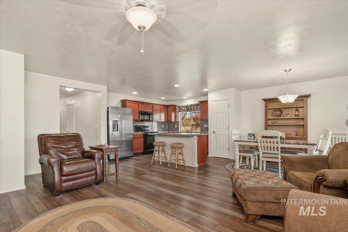 Living room featuring dark wood-style flooring, recessed lighting, a textured ceiling, and ceiling fan