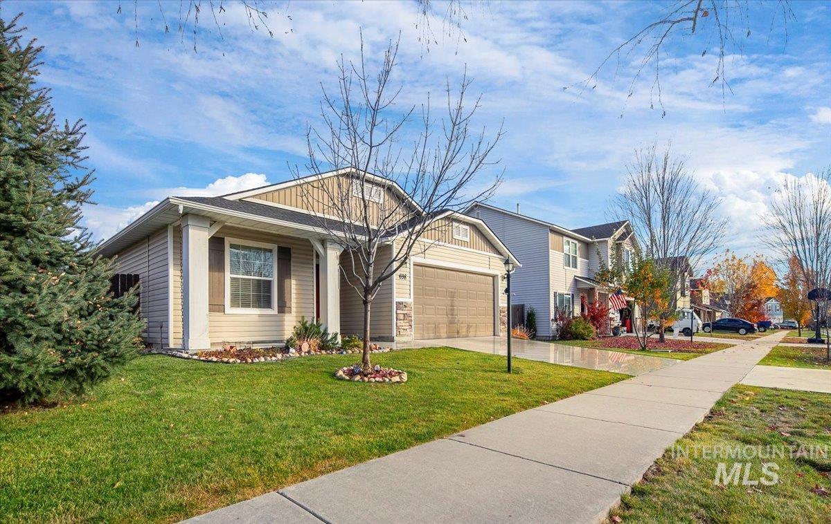 View of front facade with driveway, a front lawn, a garage, board and batten siding, and covered porch