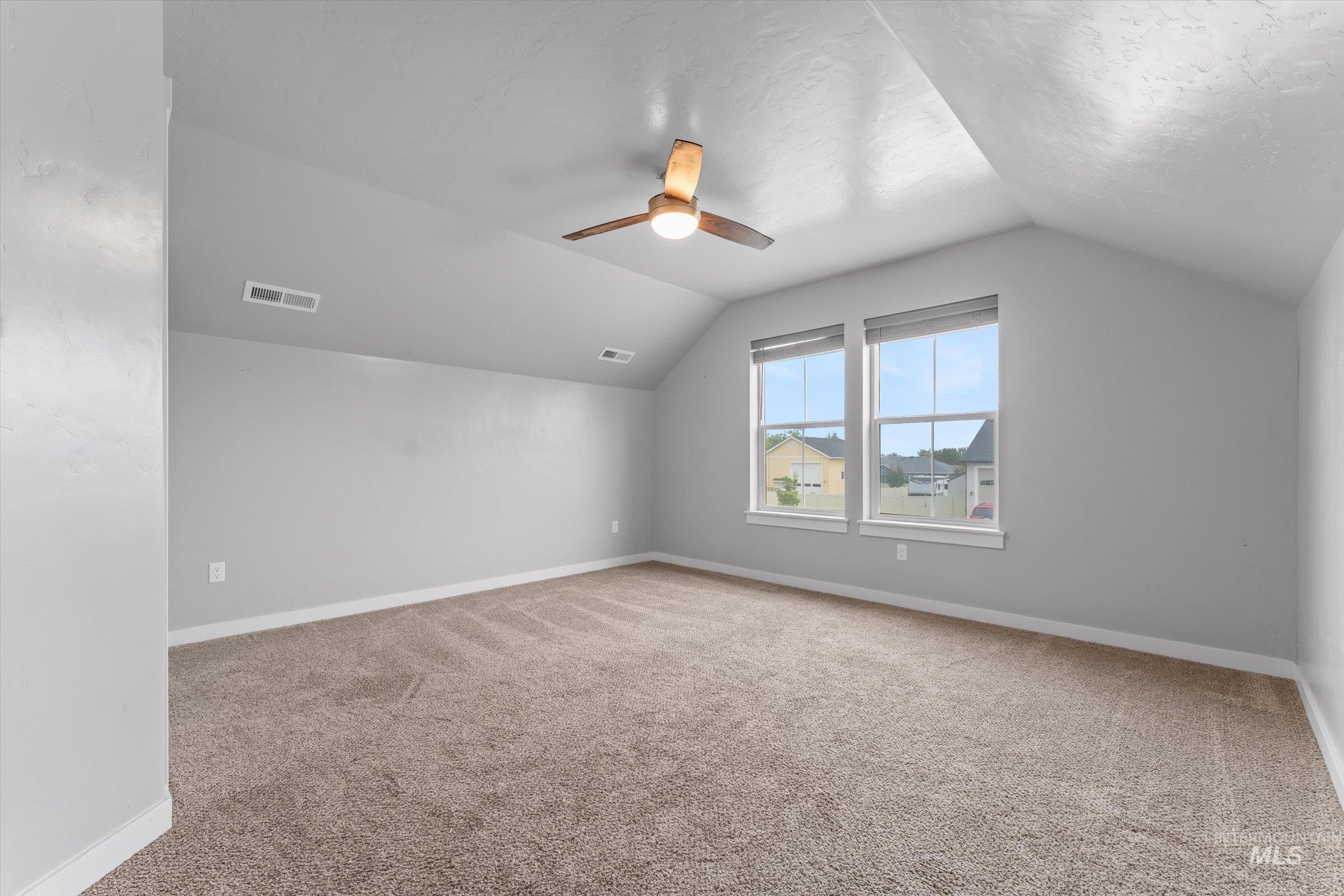 Additional living space with light carpet, lofted ceiling, and a ceiling fan