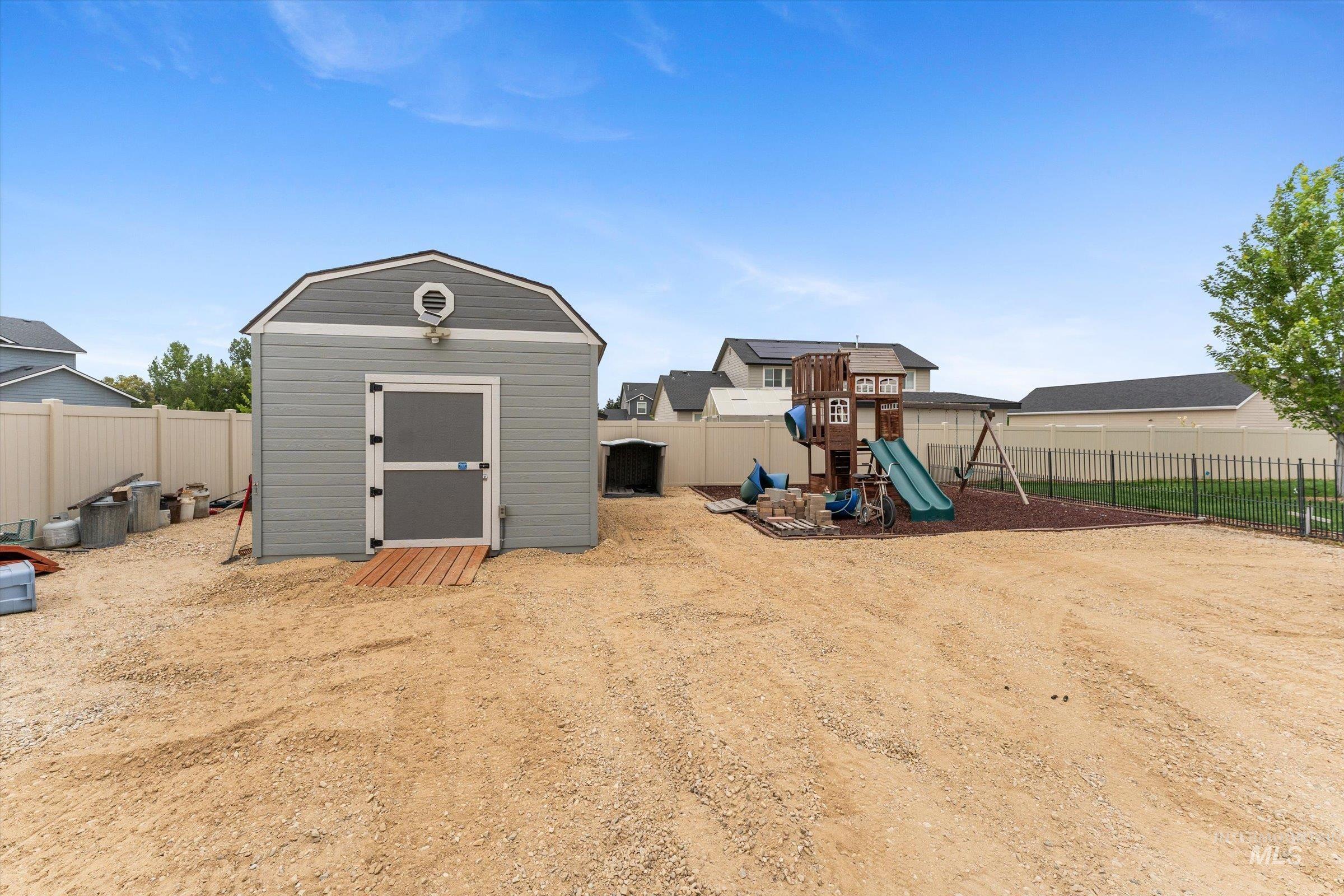 Fenced backyard with a shed and a playground