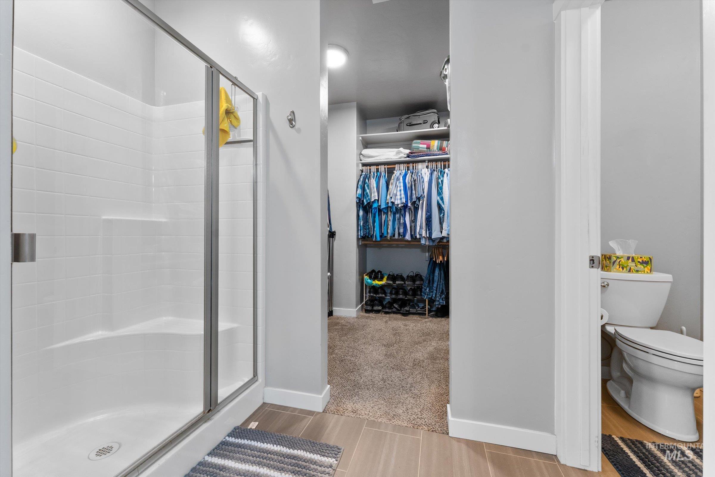 Bathroom featuring a shower stall, a spacious closet, and light tile patterned floors