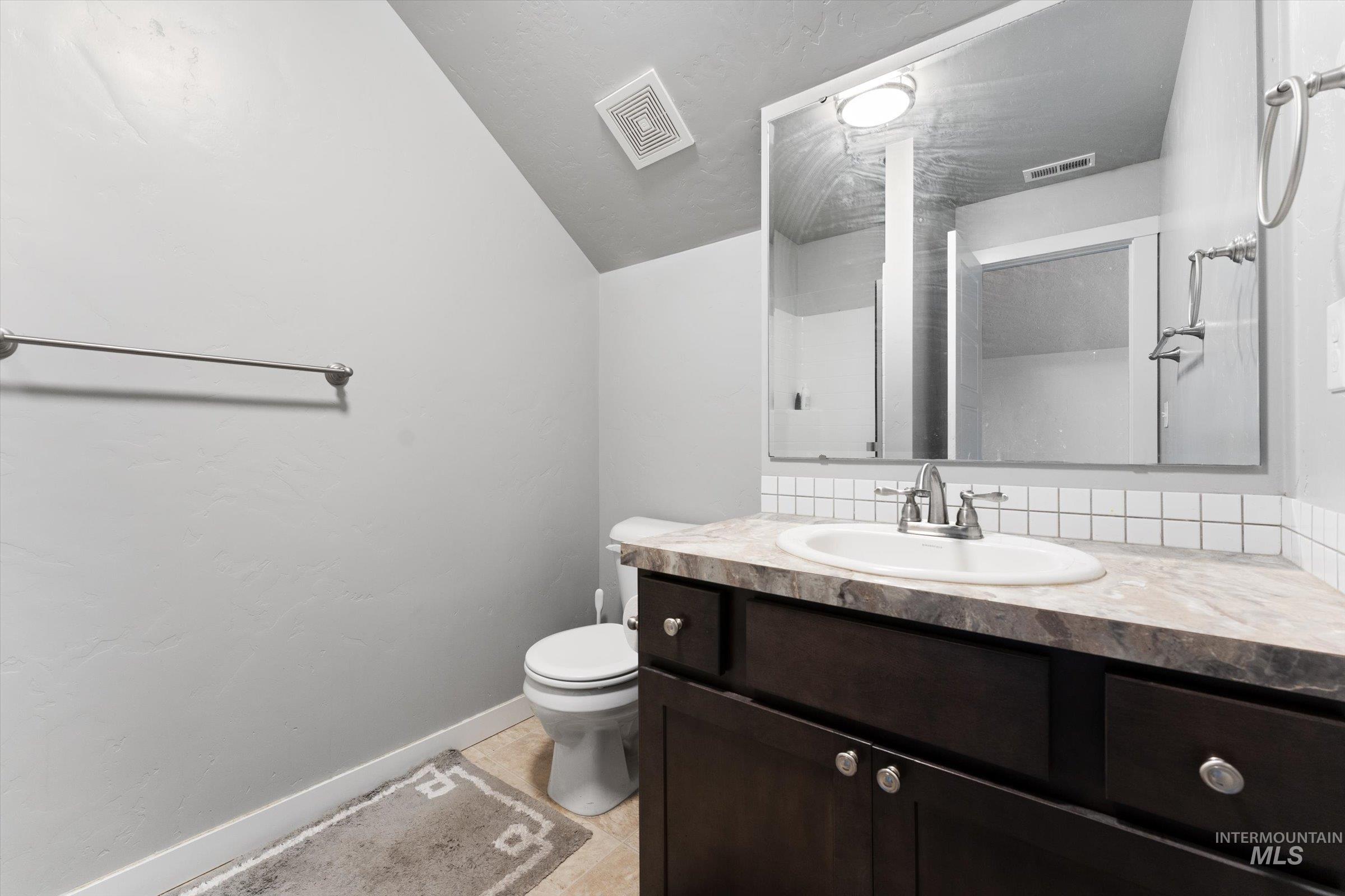 Bathroom with vanity, vaulted ceiling, and light tile patterned floors