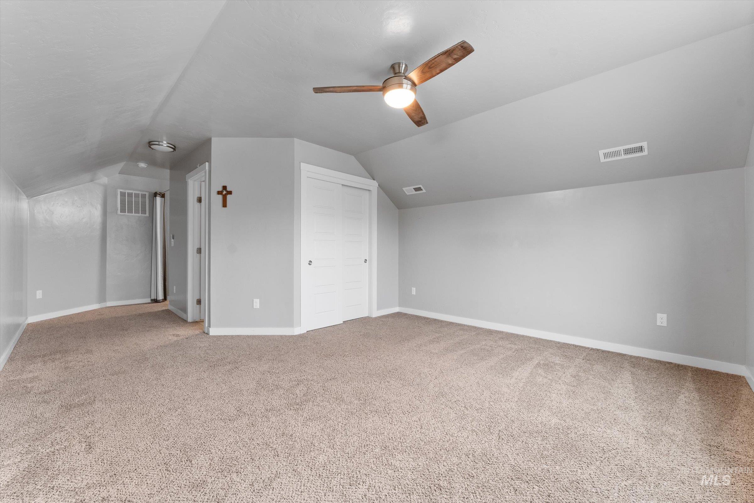 Bonus room with vaulted ceiling, light colored carpet, and a ceiling fan