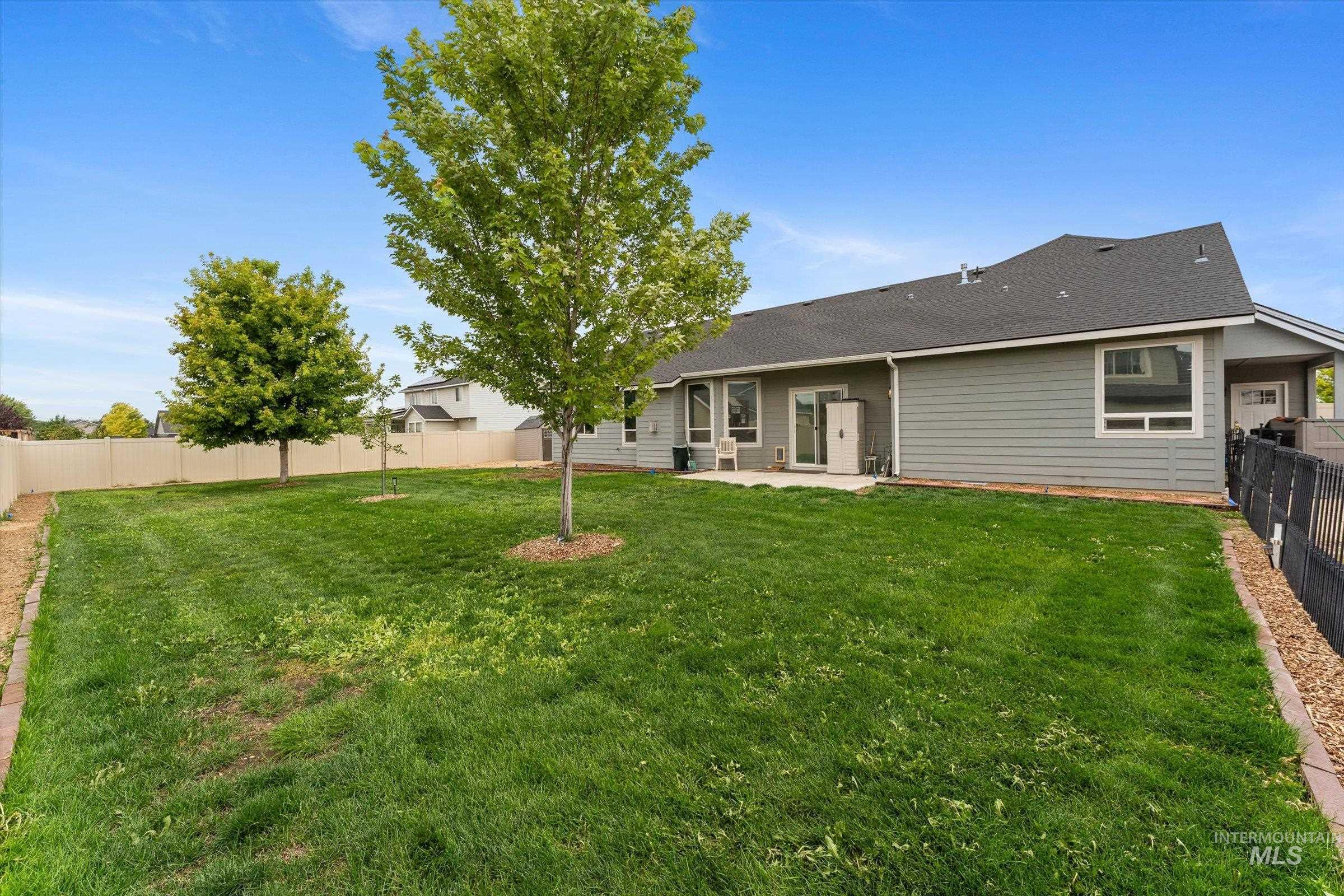 Rear view of property with a patio, a fenced backyard, and a shingled roof