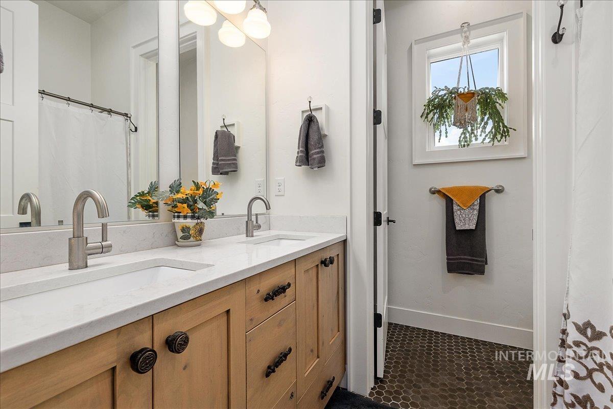 Bathroom with double vanity and dark tile patterned flooring