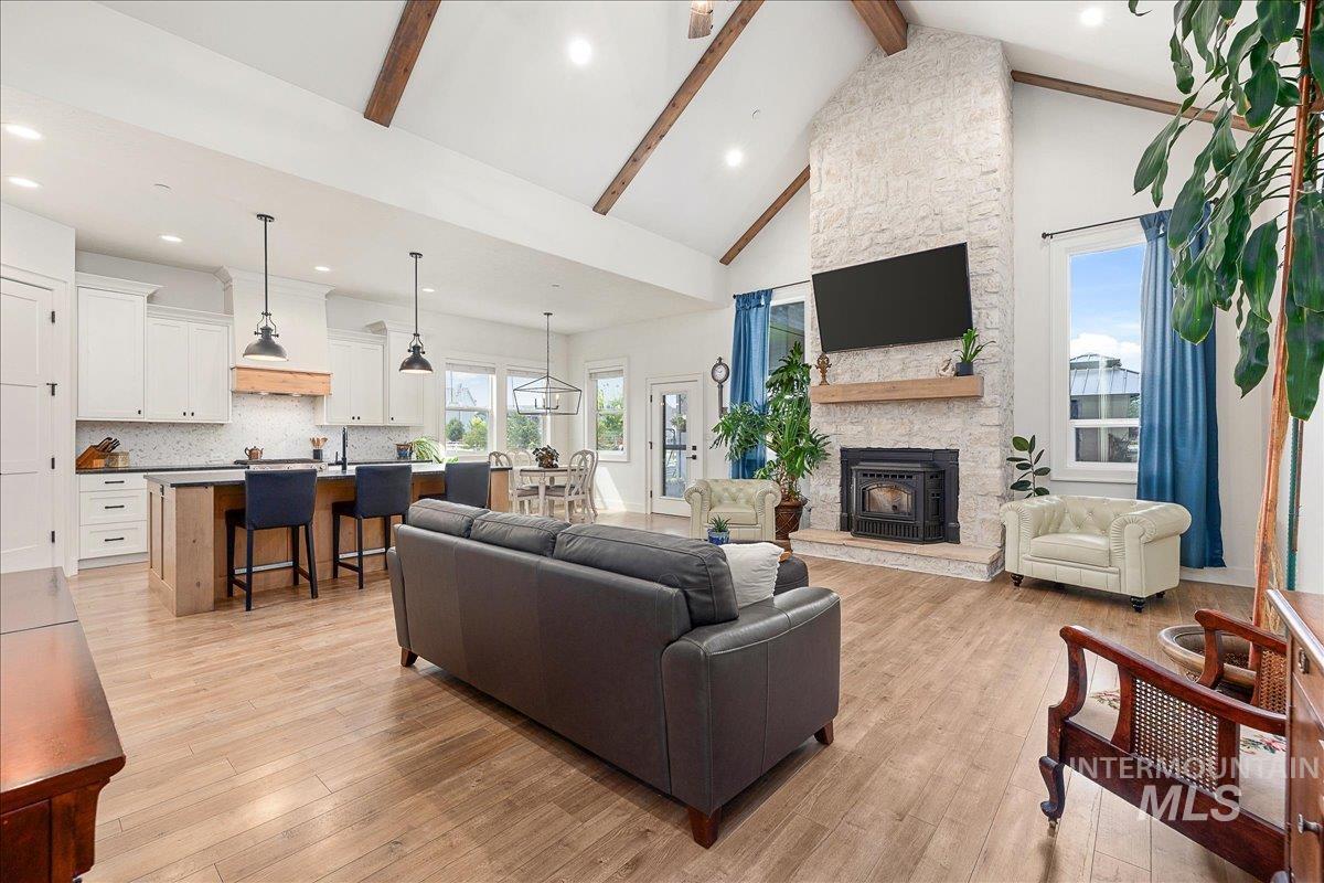 Living area with beamed ceiling, high vaulted ceiling, recessed lighting, light wood finished floors, and a fireplace