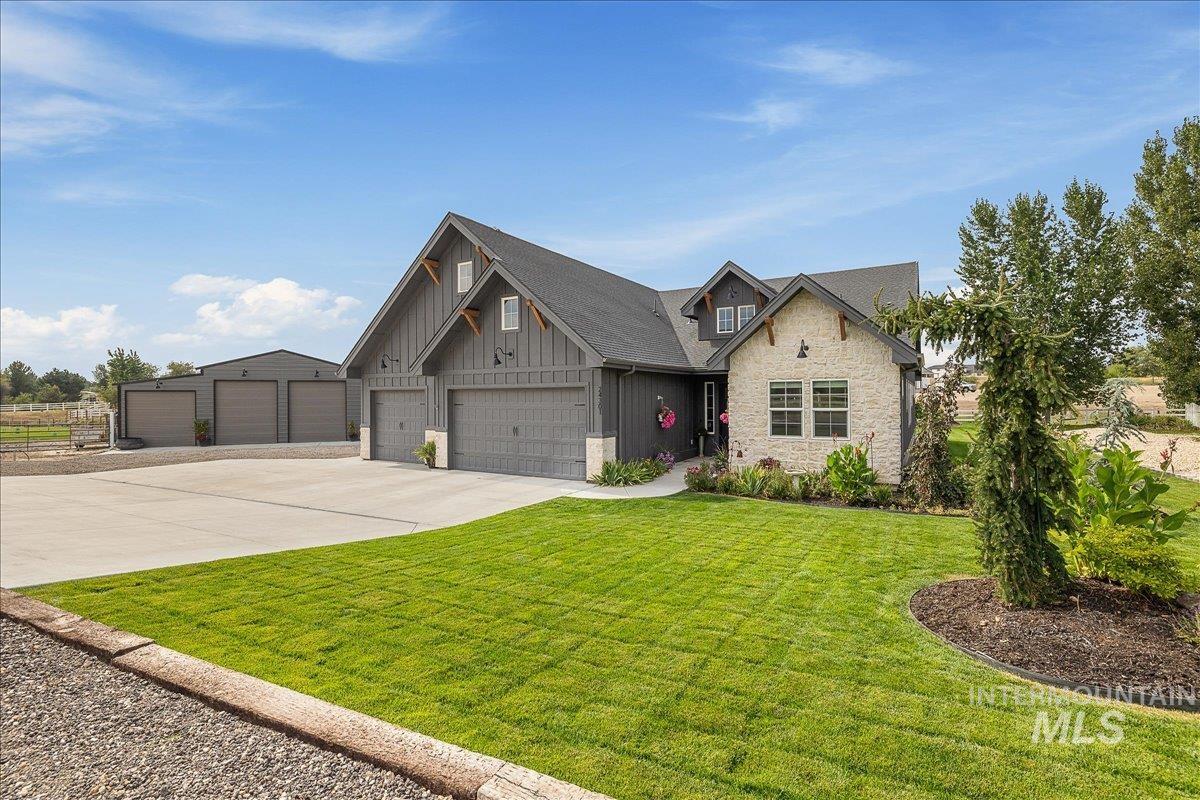 Craftsman inspired home featuring stone siding, driveway, board and batten siding, and a front lawn