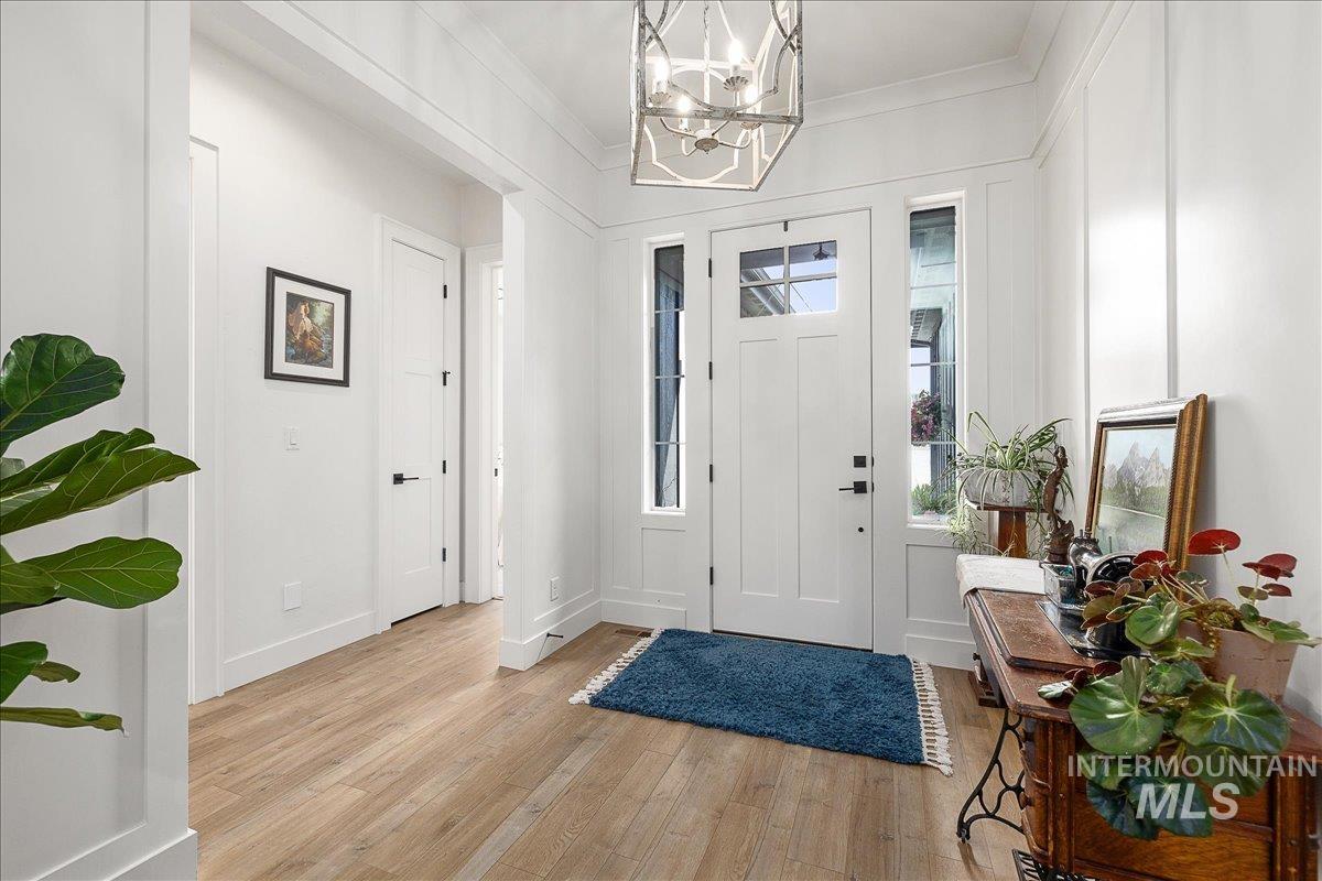Foyer featuring light wood-style flooring, ornamental molding, and a chandelier
