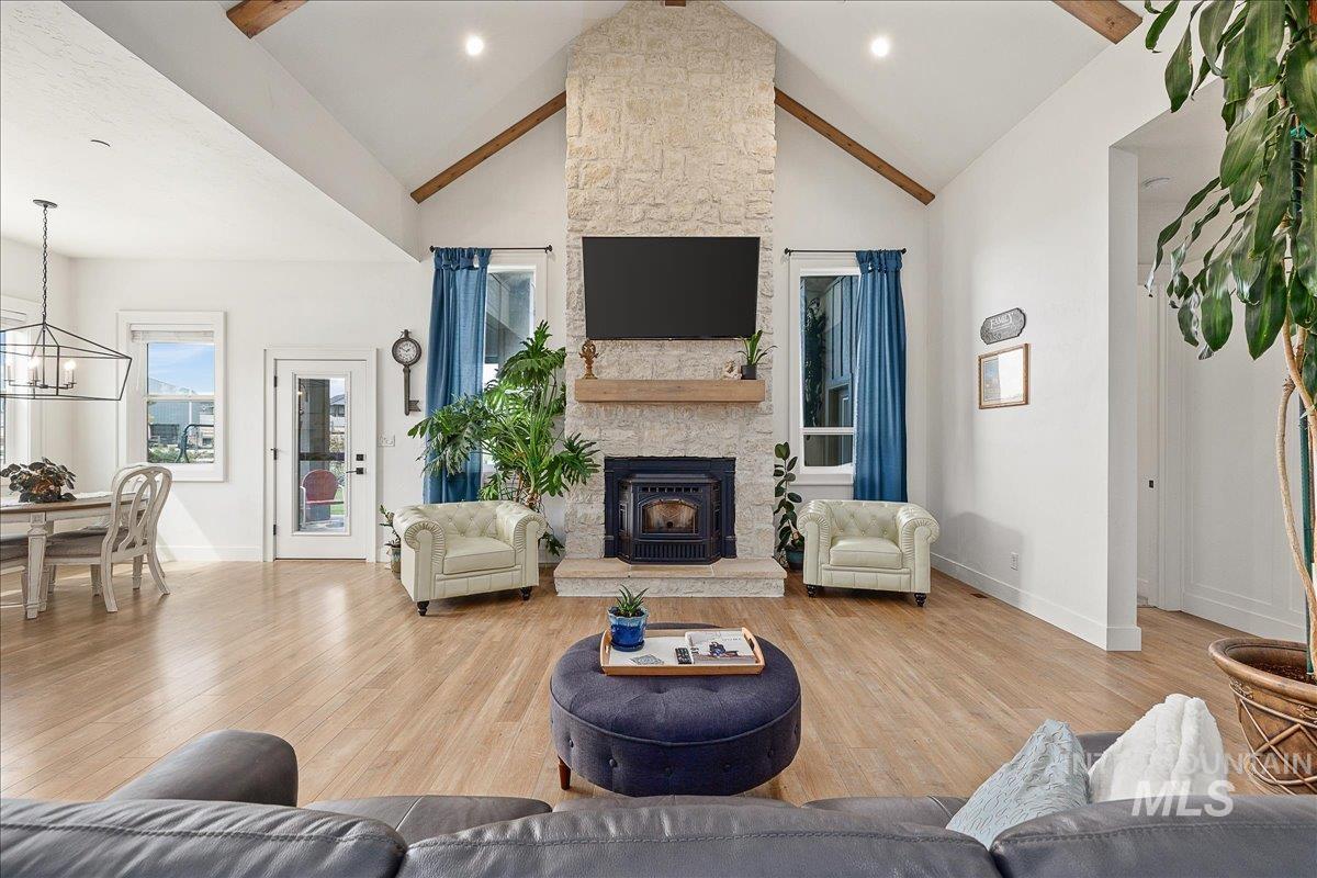 Living room featuring light wood-style flooring, high vaulted ceiling, a fireplace, recessed lighting, and a chandelier