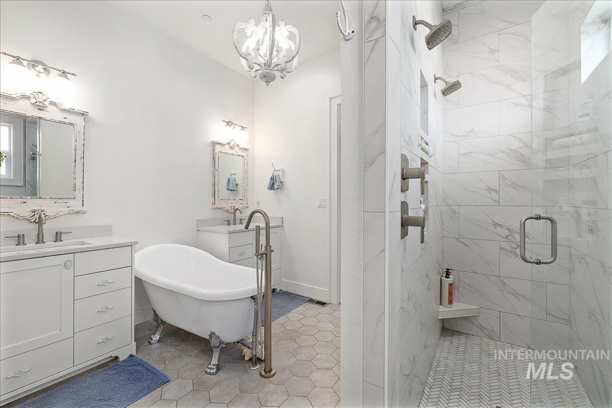 Full bath with a freestanding bath, a stall shower, vanity, and light tile patterned floors