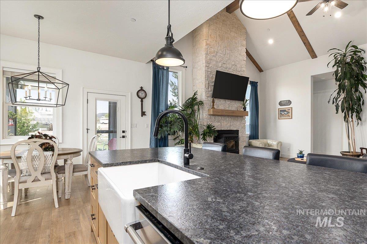 Kitchen with decorative light fixtures, light wood-style floors, a fireplace, high vaulted ceiling, and open floor plan