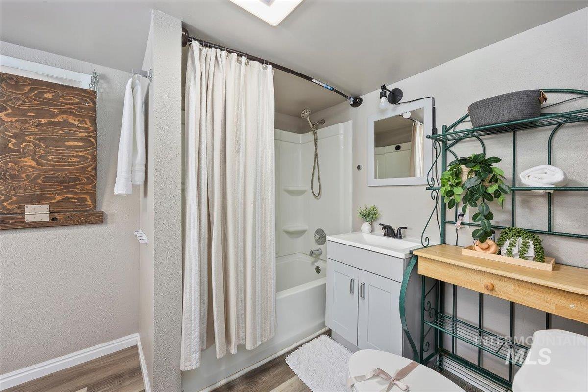 Full bathroom featuring shower / bath combination with curtain, vanity, and wood finished floors