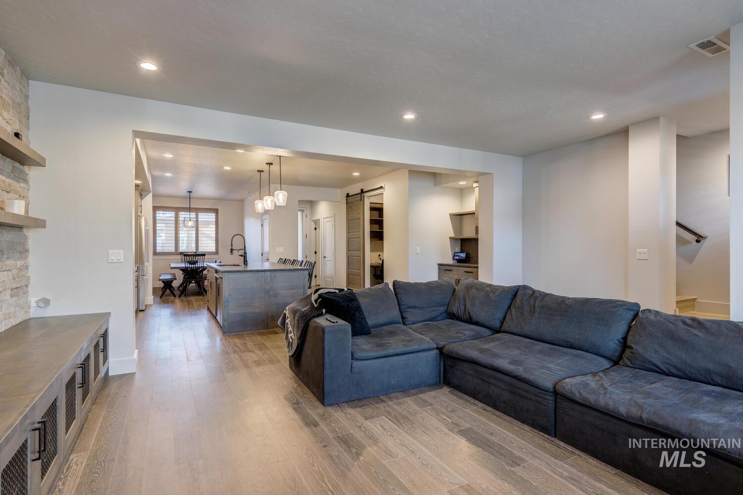 Living area with a barn door, light wood-style floors, and recessed lighting