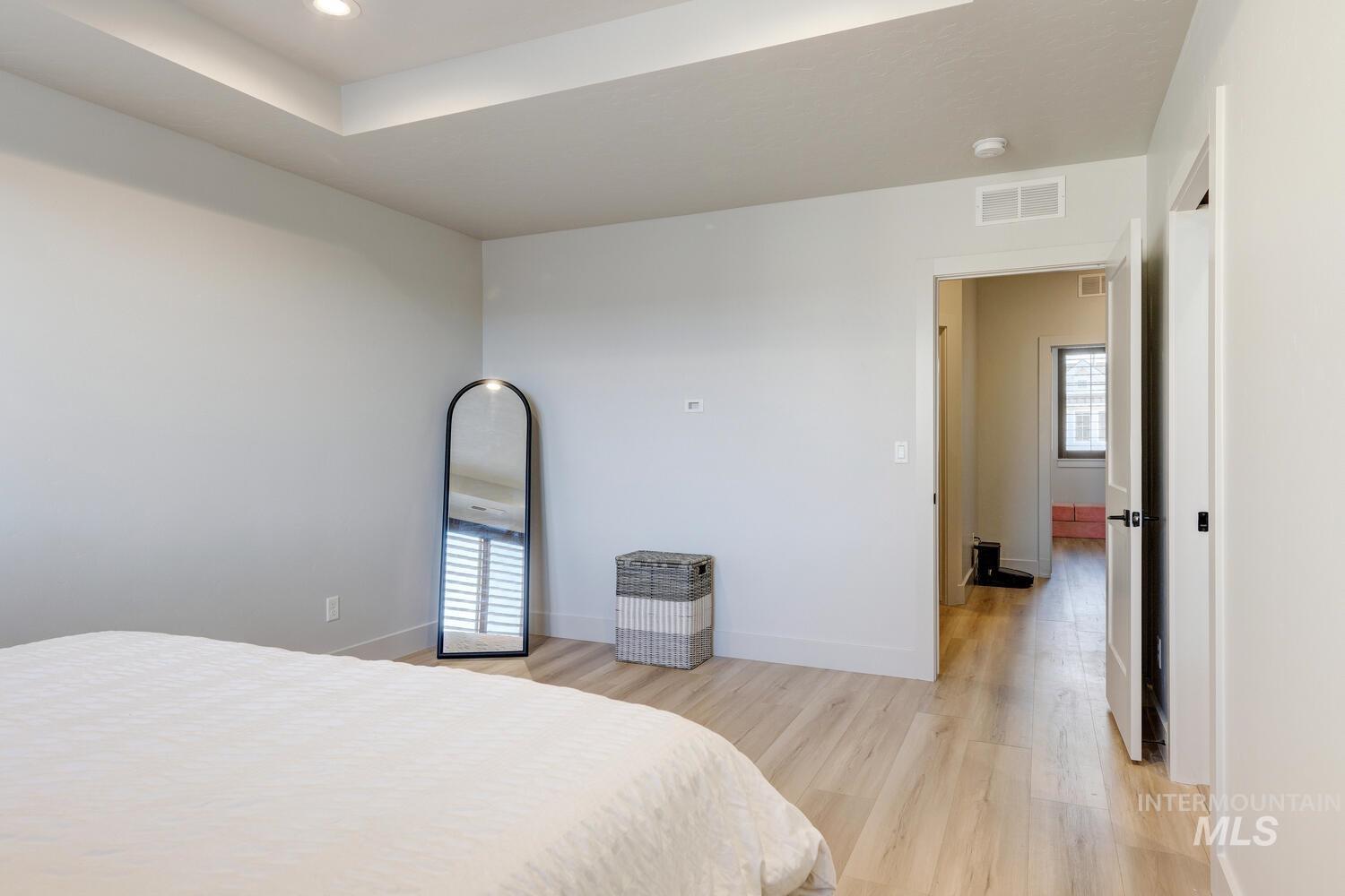 Bedroom featuring light wood-style floors and a tray ceiling