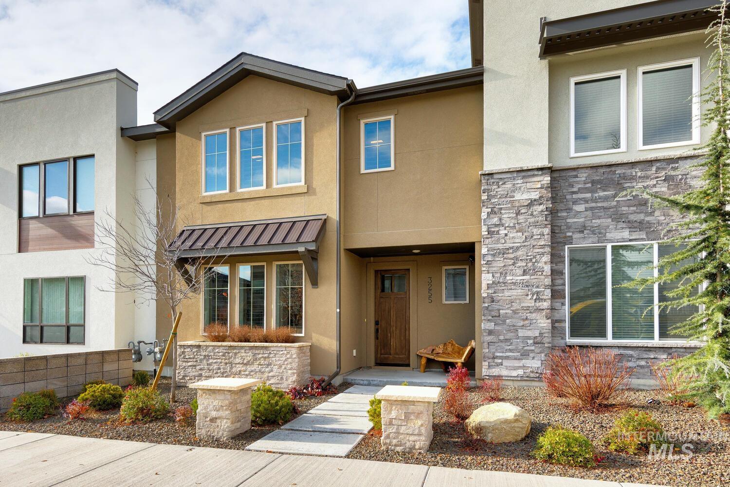 View of front of home with stone siding, stucco siding, a metal roof, and a porch