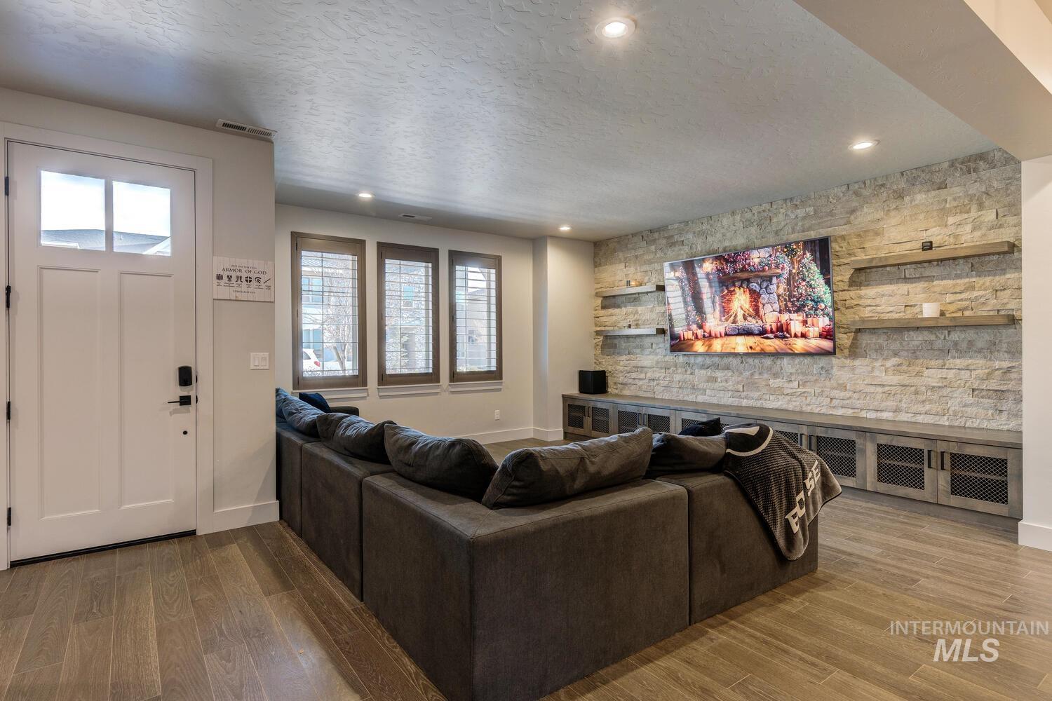 Living area featuring light wood finished floors, a textured ceiling, recessed lighting, and an accent wall