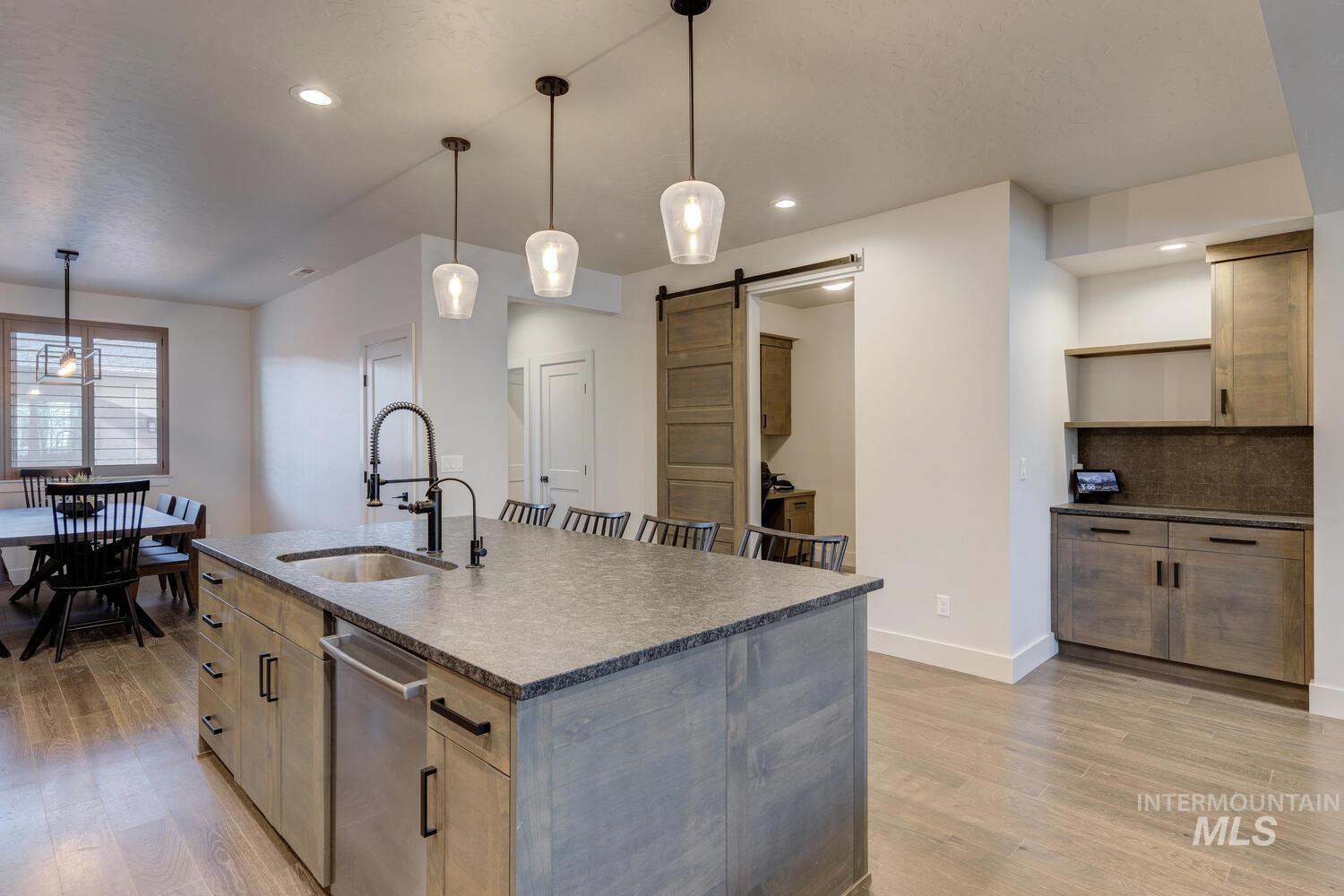 Kitchen featuring a barn door, light wood-style flooring, pendant lighting, and recessed lighting